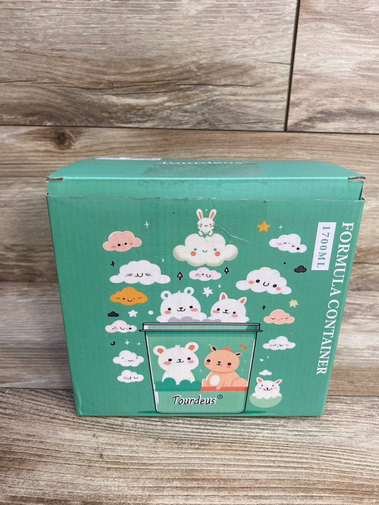 Front view of Ankou Formula Container in original Tourdeus green retail box with cartoon bunny and cloud graphics on wood plank floor
