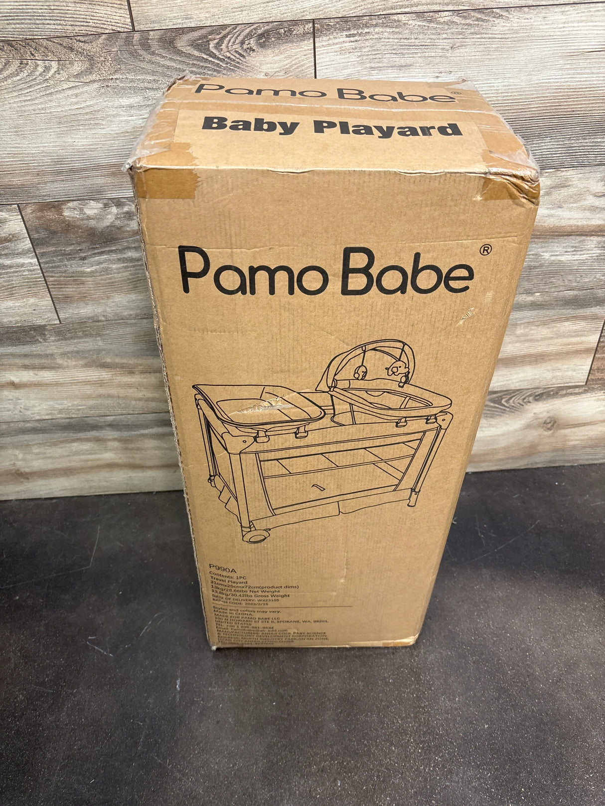 Pamo Babe baby playard cardboard box on wood floor, product packaging photo