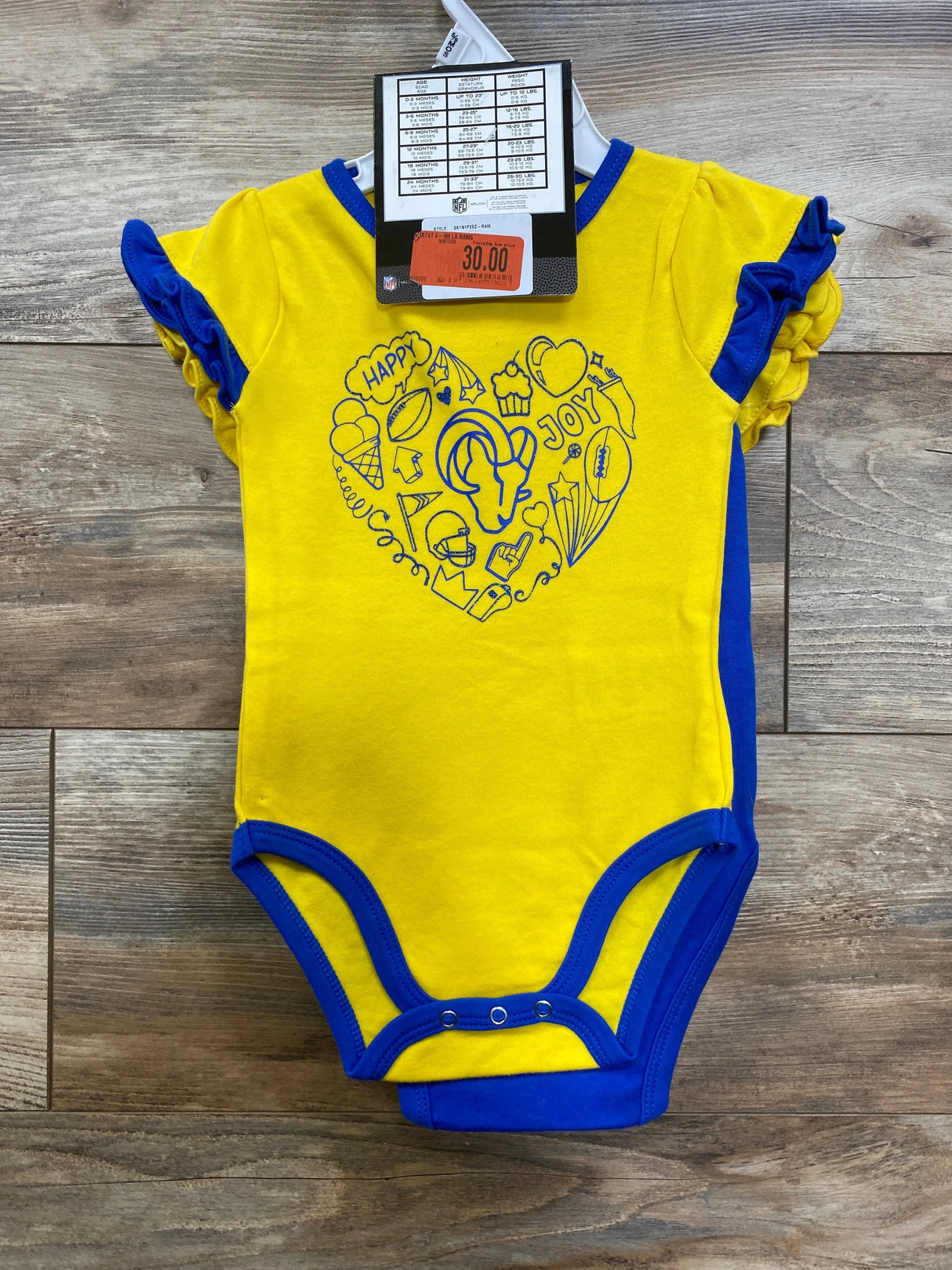 Yellow and blue baby onesie with heart doodle design and NFL logo on wood floor