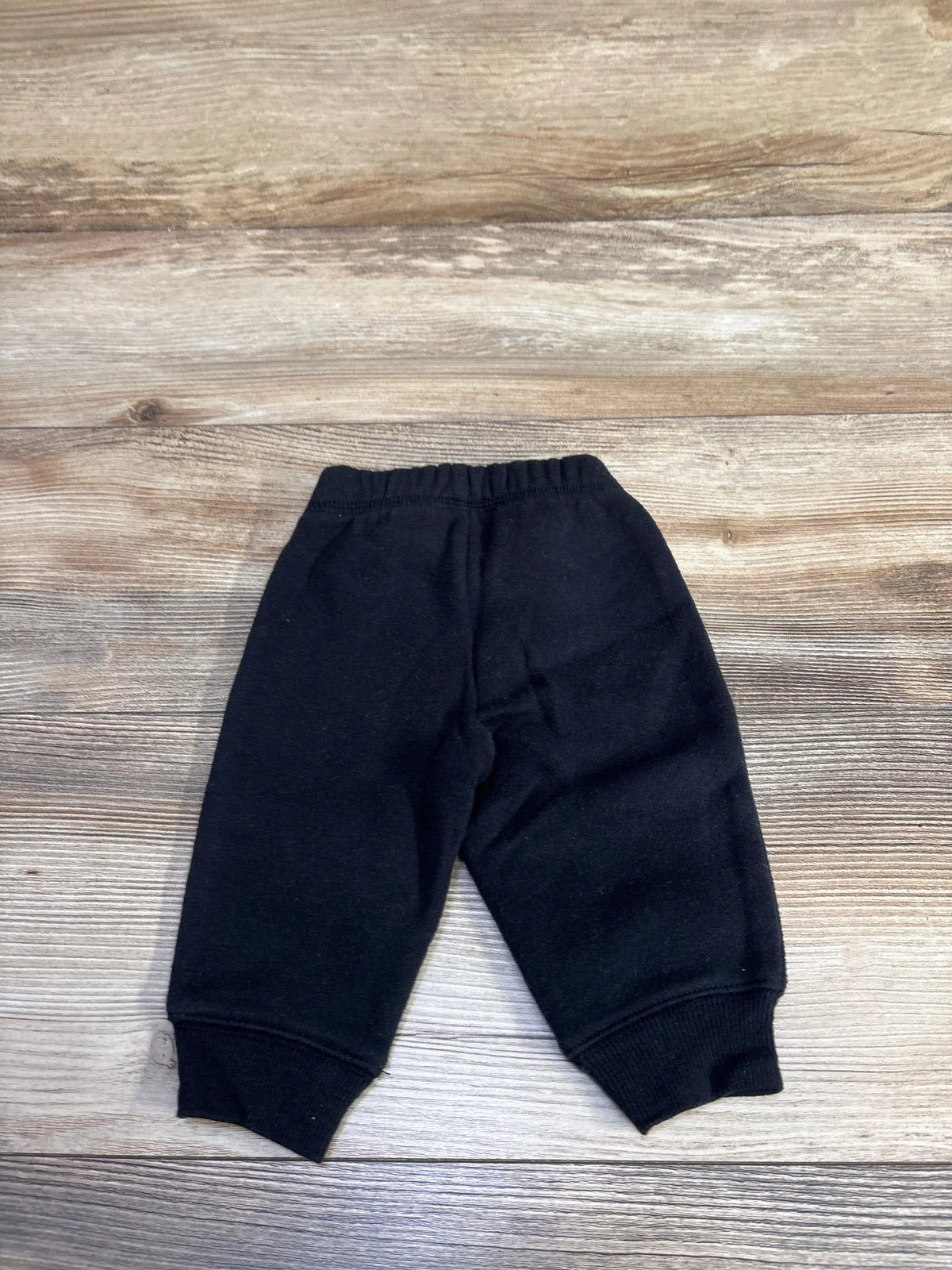 Flat lay of Jumping Beans baby drawstring joggers showing elastic waistband and ribbed cuffs on light wood background