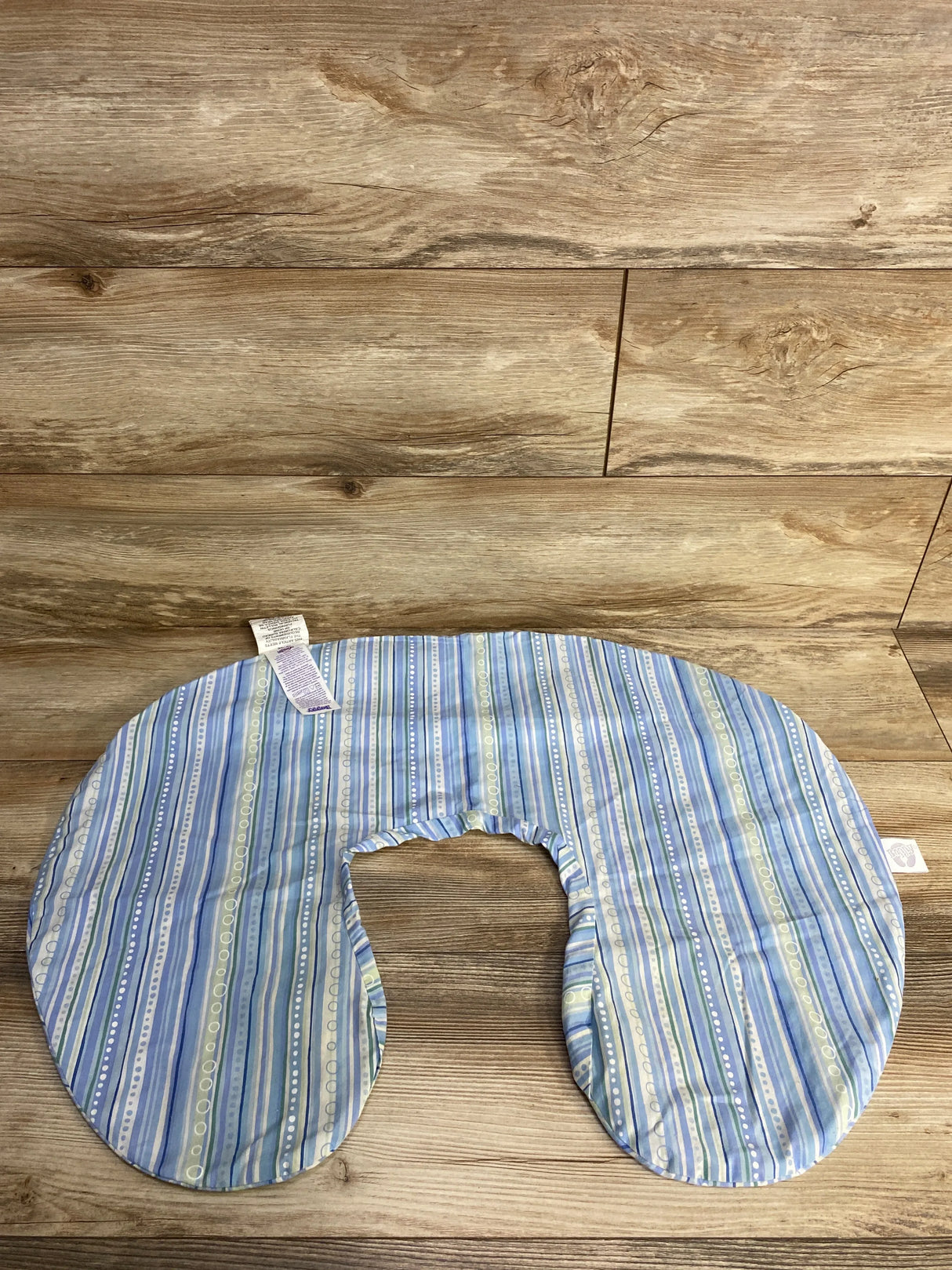 Top down view of Boppy nursing pillow cover in blue and green stripes showing U shape and elastic inner seam on wooden floor