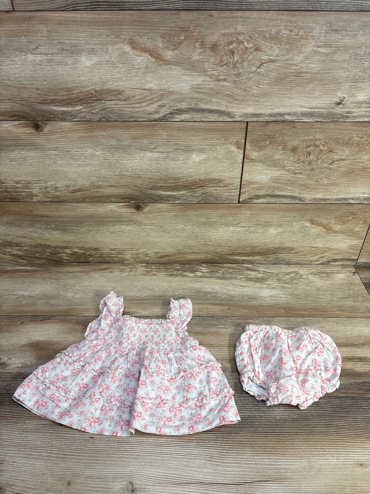 Flat lay of Janie & Jack Emily floral smocked two-piece set with ruffle straps and matching bloomers on wood background