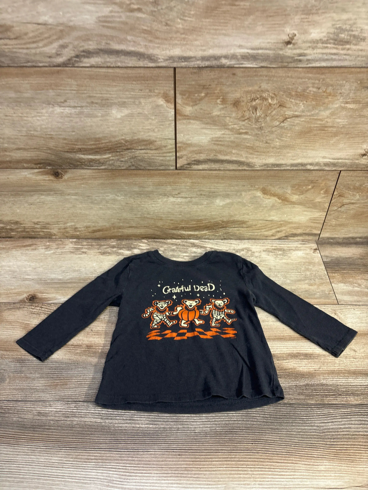 Front view of Old Navy Grateful Dead shirt showcasing grey cotton, graphic print, and long sleeves on a wood floor
