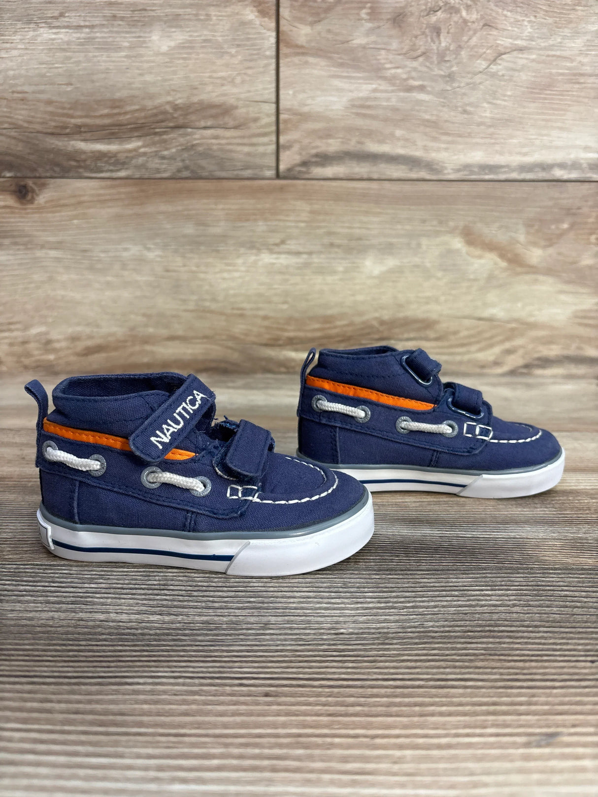 Nautica toddler boat shoes navy blue with orange accents on wood background