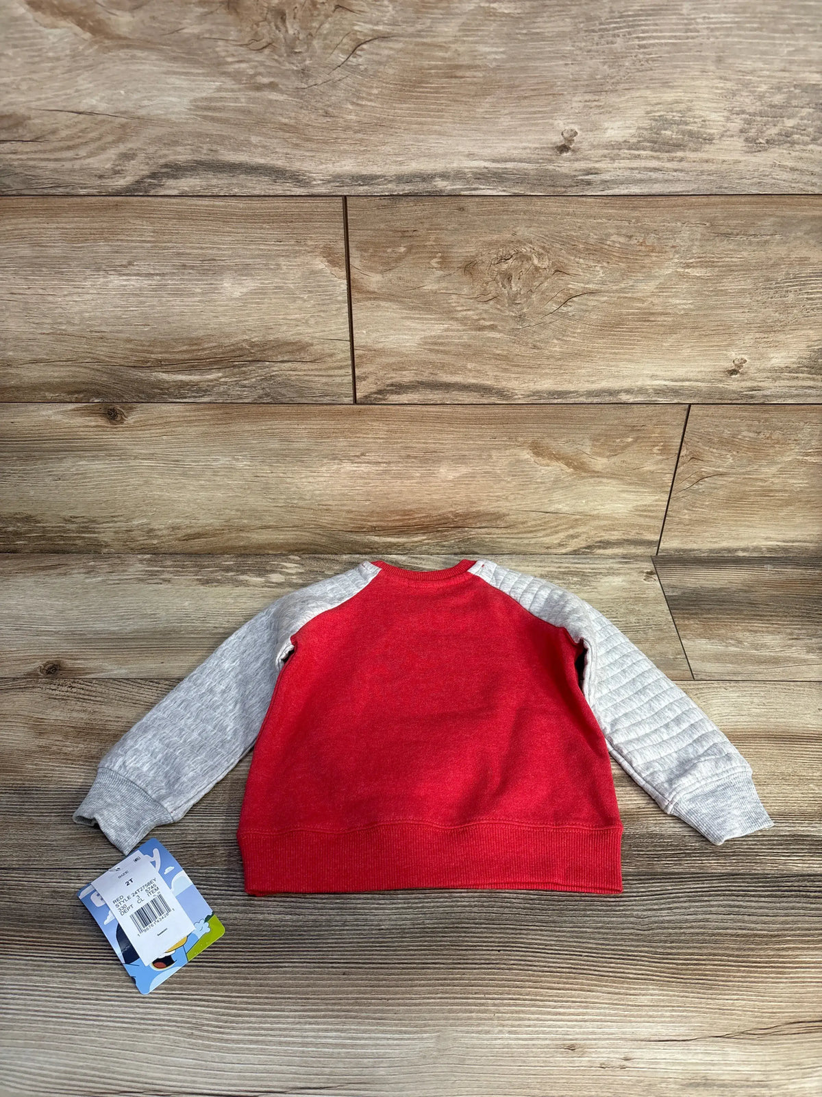Back view of red Bluey Smoochy Kiss pullover sweatshirt with gray sleeves on a wood-look floor