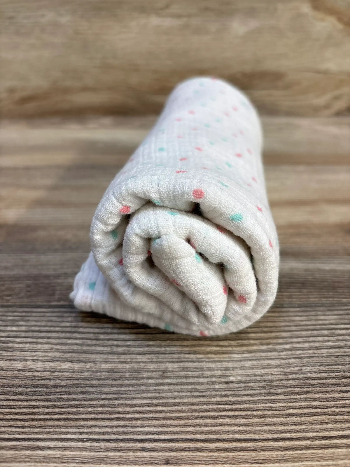 Soft baby swaddle blanket with pink and teal polka dots, ideal for newborns and infants