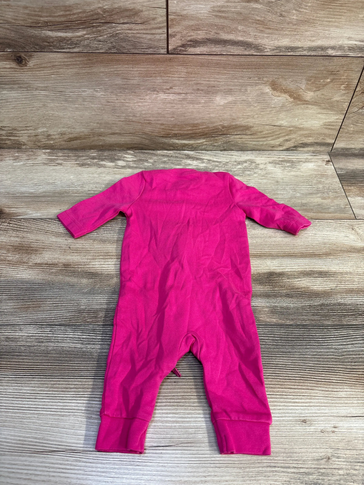 Primary Organic solid pink newborn baby sleeper laid flat on a wooden background