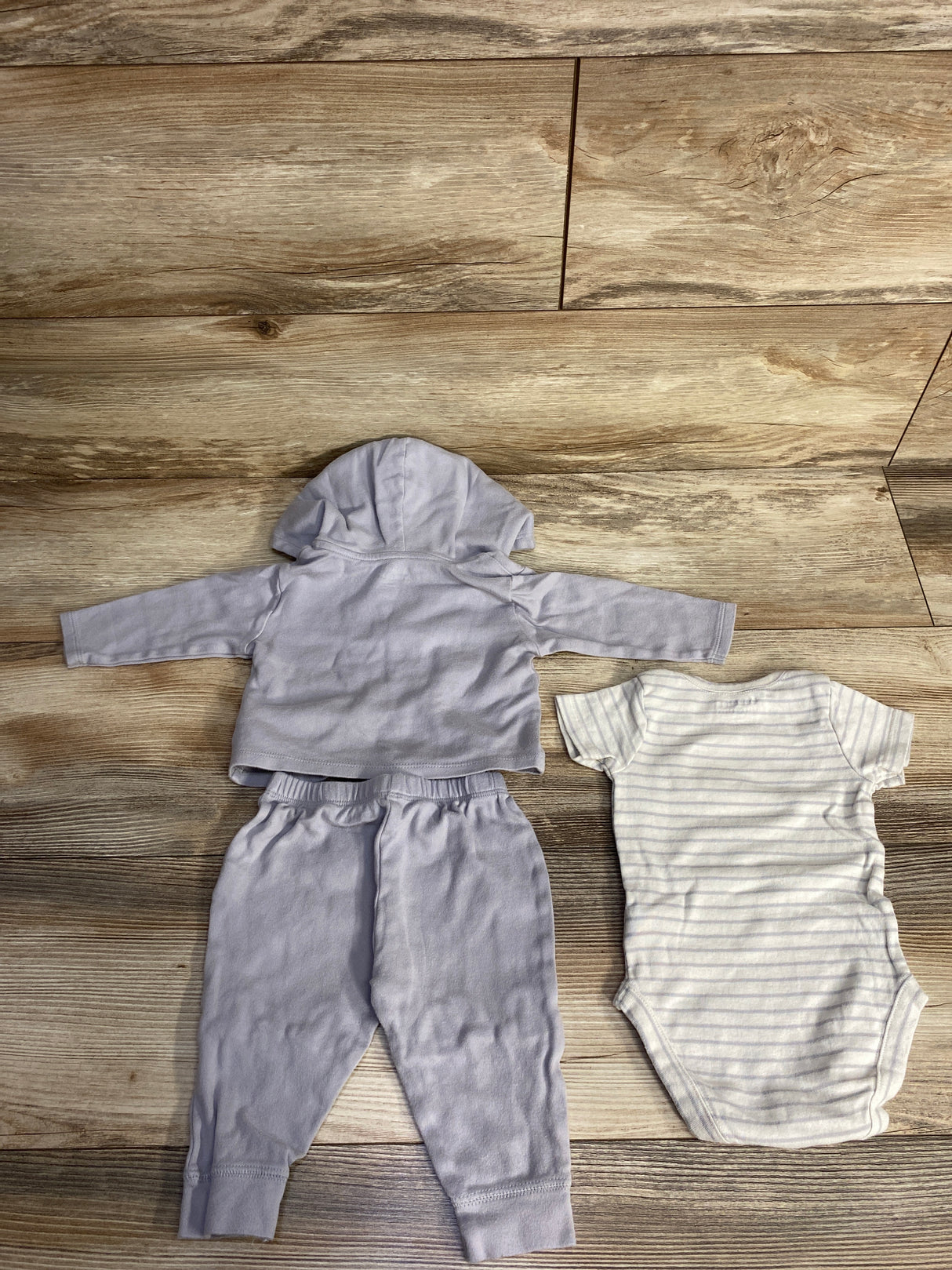 Gray hooded baby sweatshirt and pants set with white striped short-sleeve baby bodysuit on wooden floor