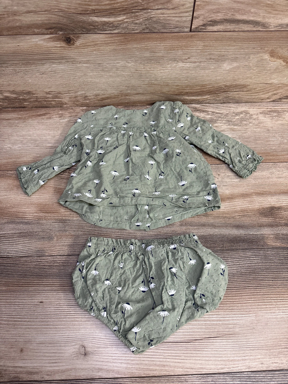 Vintage green baby girl long sleeve top and bloomer set with white floral print on wood background