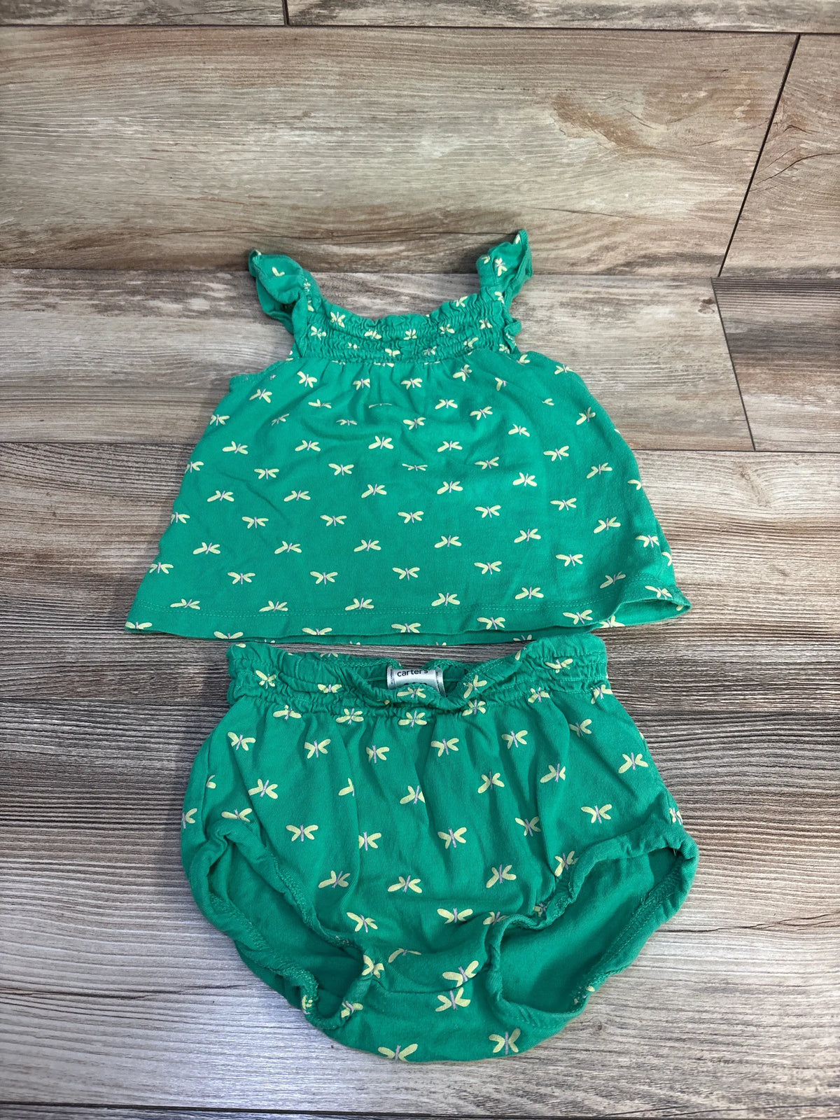 Front view of Carter’s 2pc smocked tank top and short set showcasing green fabric with cream butterfly print on wood-look background
