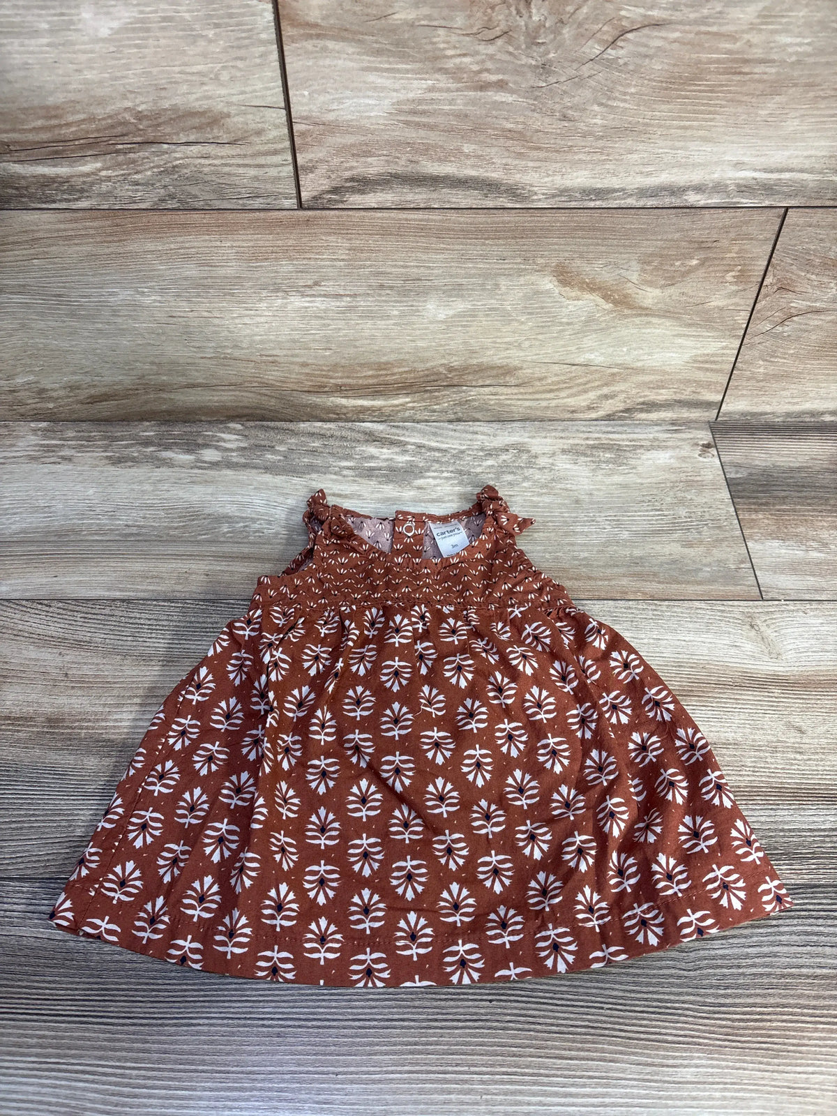 Top-down view of the Just One You dress and bloomers set, showing the brown patterned sleeveless dress on a wood-look floor
