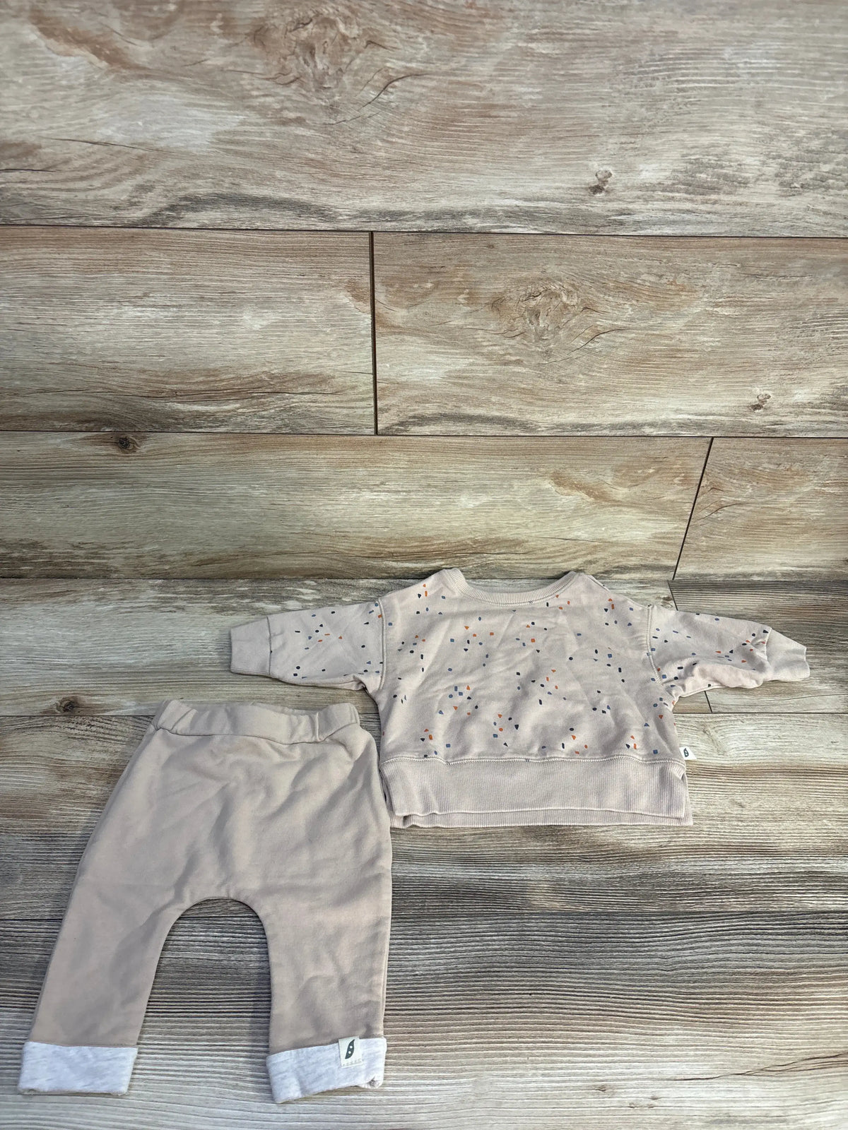 Top down view of Easy Peasy beige organic long sleeve shirt and pants set showcasing a speckled shirt on a wood floor