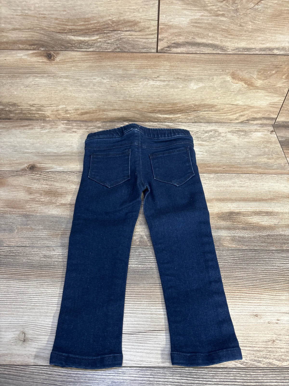 Back view of navy BOLO pull-on jeggings showcasing elastic waistband and two back pockets on a wood-look floor