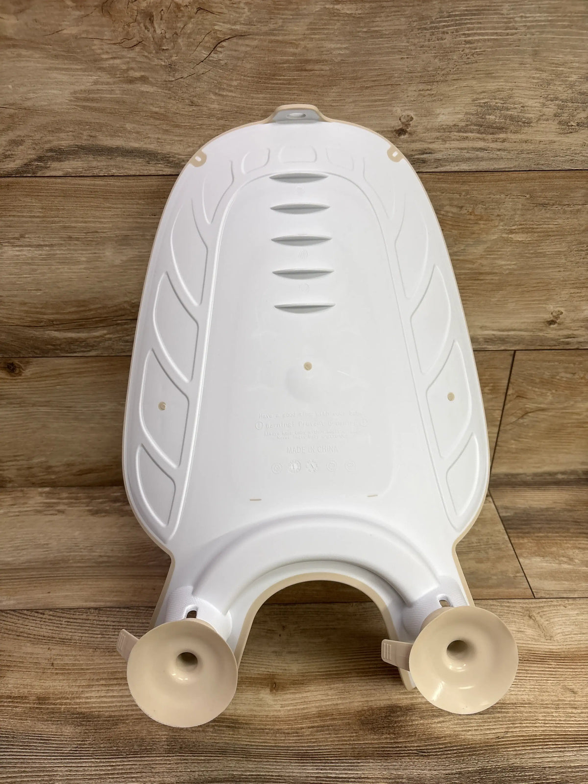 Rear view of Malang Honey baby bidet sink bath support showcasing beige suction cups and molded backrest on a wood floor