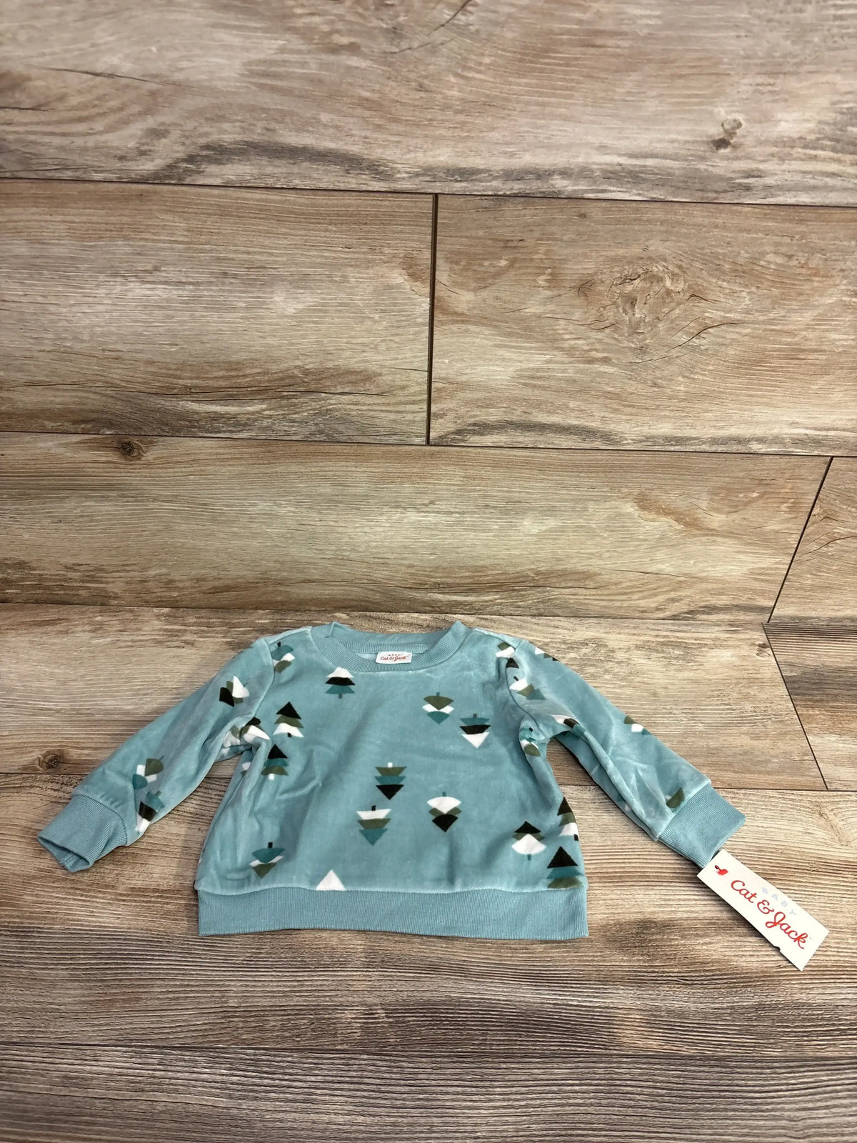 Blue long sleeve baby sweatshirt with geometric shapes pattern and Cat & Jack brand tag on wooden floor