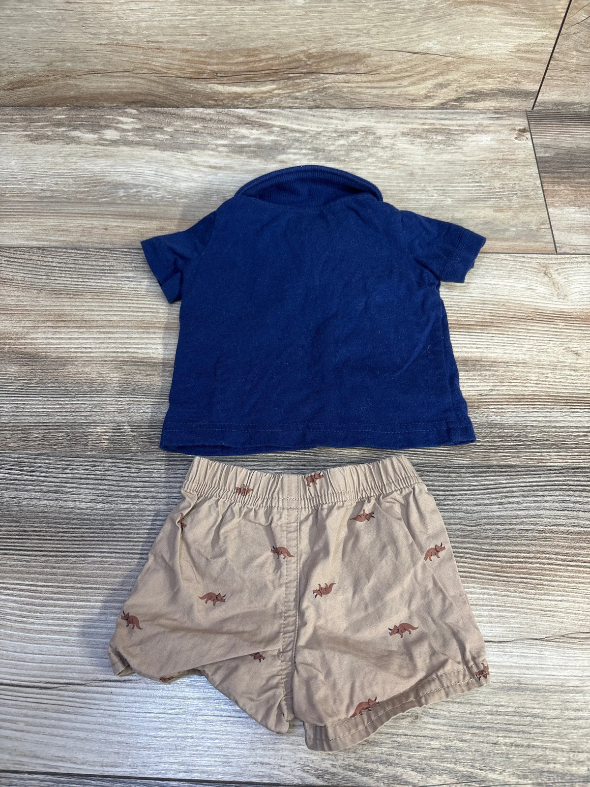 Top view of Carter’s two-piece polo shirt and shorts set showcasing a navy short-sleeve polo on a woodgrain background