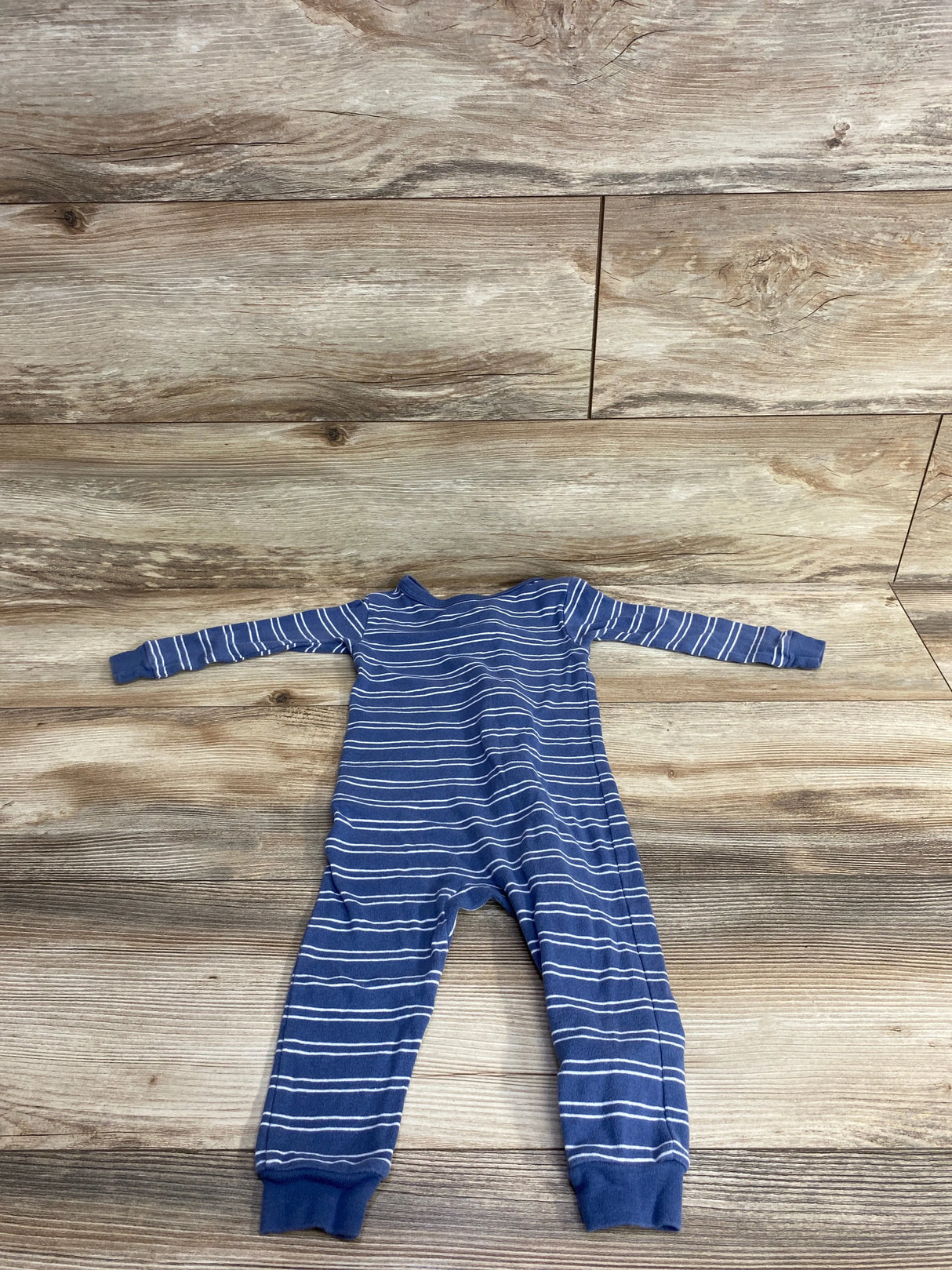 Blue and white striped long-sleeve baby onesie laid flat on wood floor background