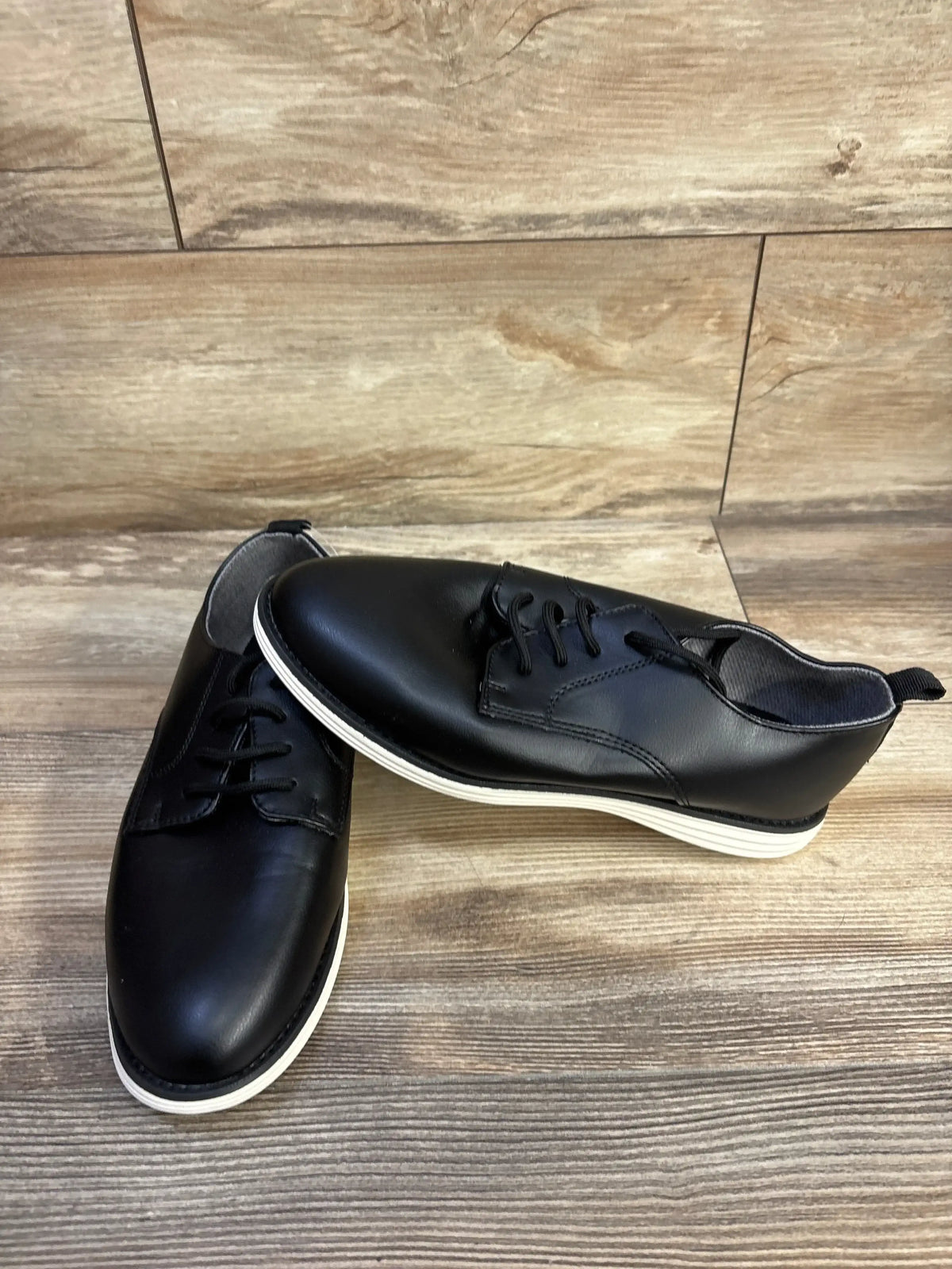 Angled view of Cat & Jack Alfi dress shoes in black, size 6Y showcasing lace closure with wood-look flooring