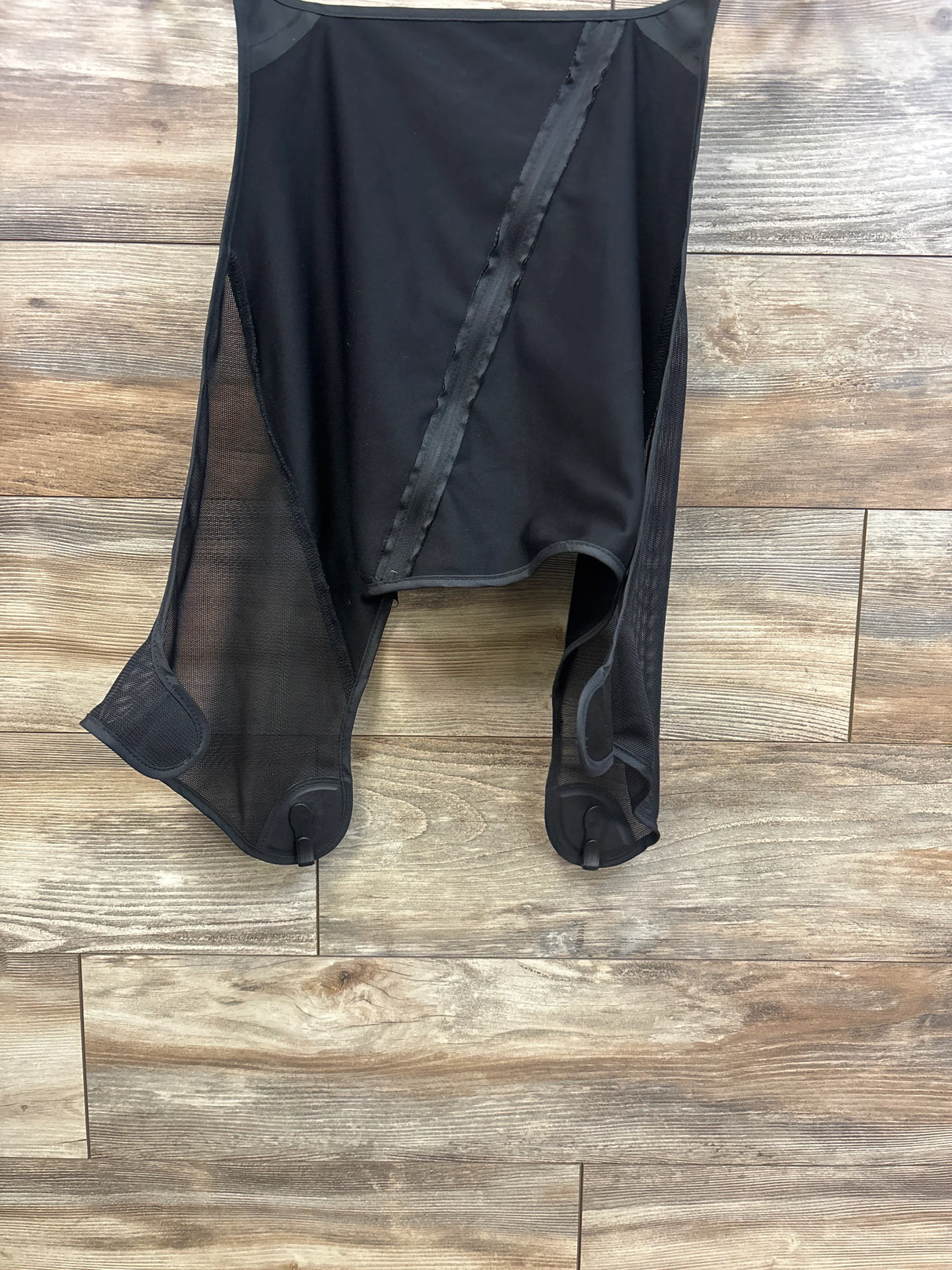 Front view of stroller sun shade extension with black canopy, mesh side panels, and attachment clips on wood floor