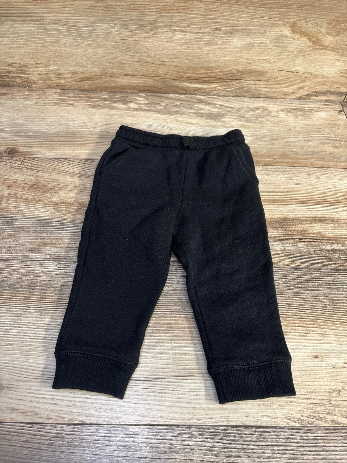 Front view of Cat & Jack drawstring joggers showcasing relaxed fit, side pockets, and ribbed cuffs on a wood-grain background