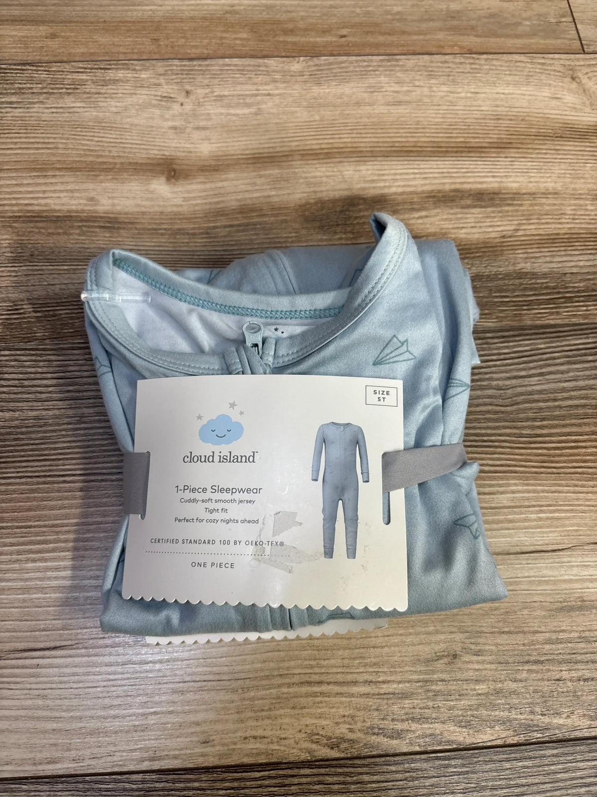 Folded view of a blue Cloud Island footless sleeper showcasing the front zipper on a wood-grain surface