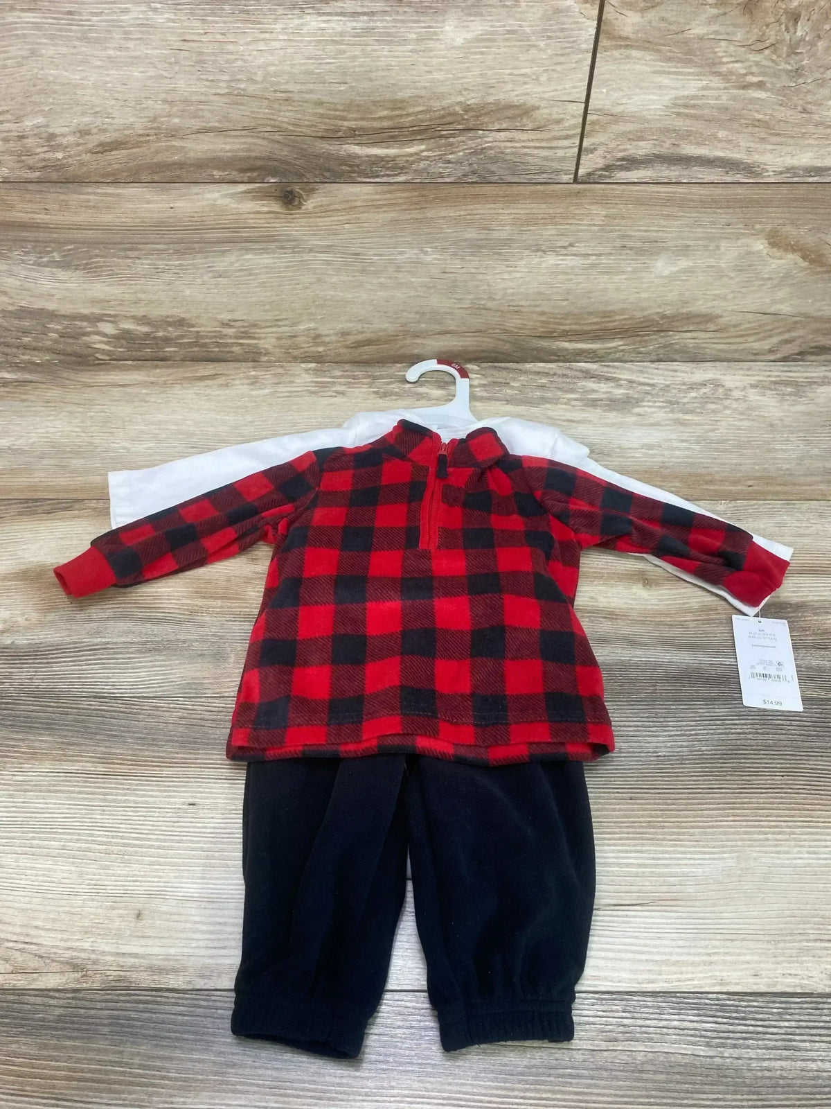 Front view of 3-piece baby fleece set: red-black buffalo pullover, white tee, navy pants on hanger on wood background
