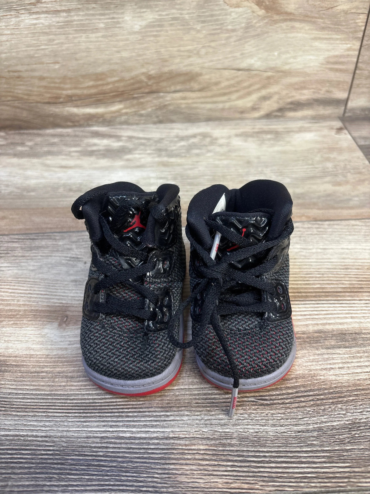 Black and red toddler Jordan sneakers on wood floor, kids footwear resale