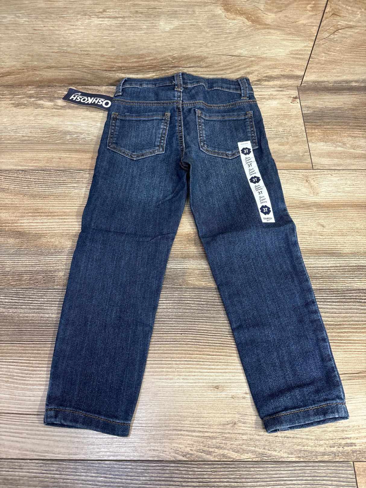 OshKosh dark wash denim jeans for toddlers size 3T on wood floor