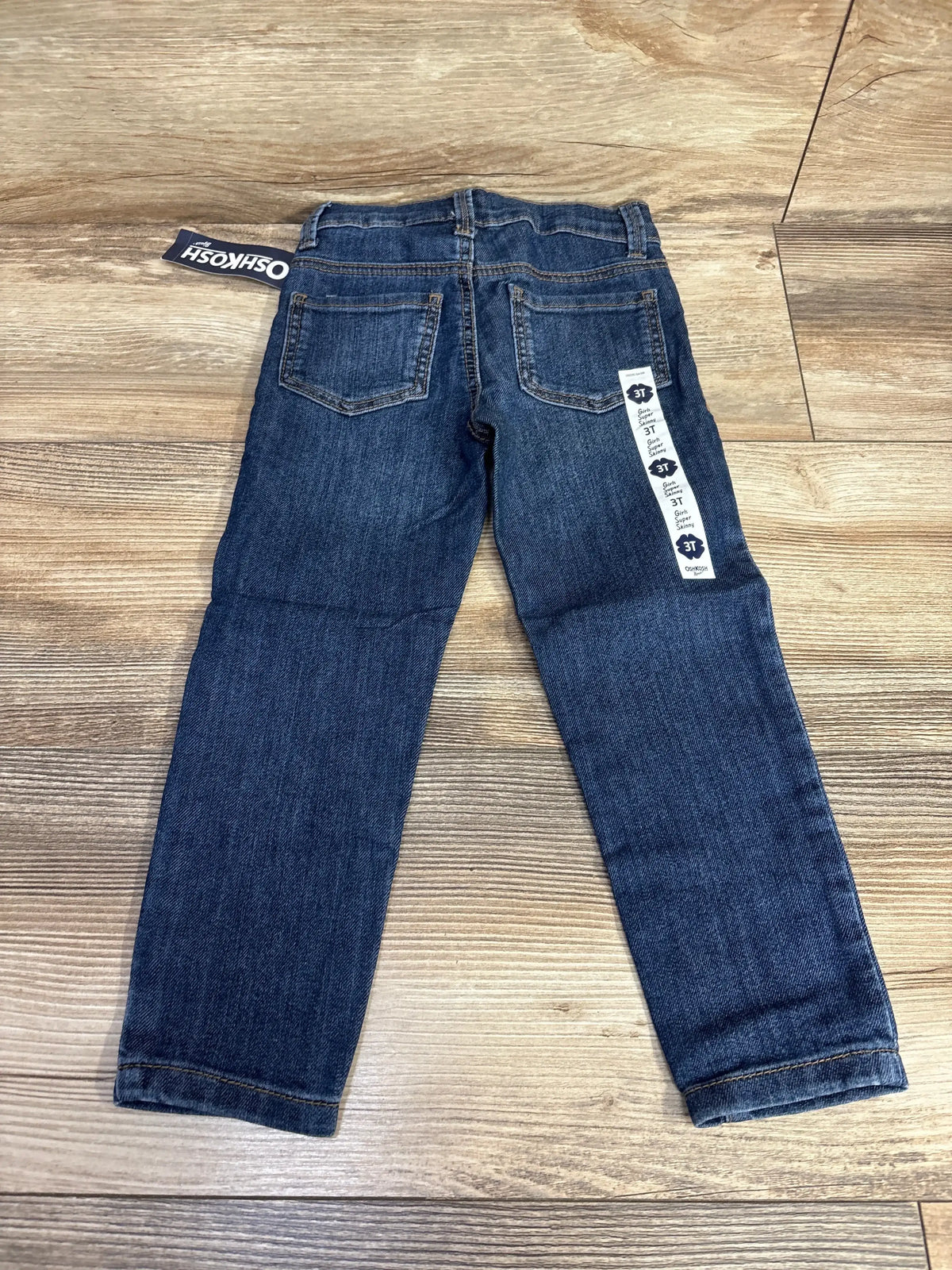 OshKosh dark wash denim jeans for toddlers size 3T on wood floor
