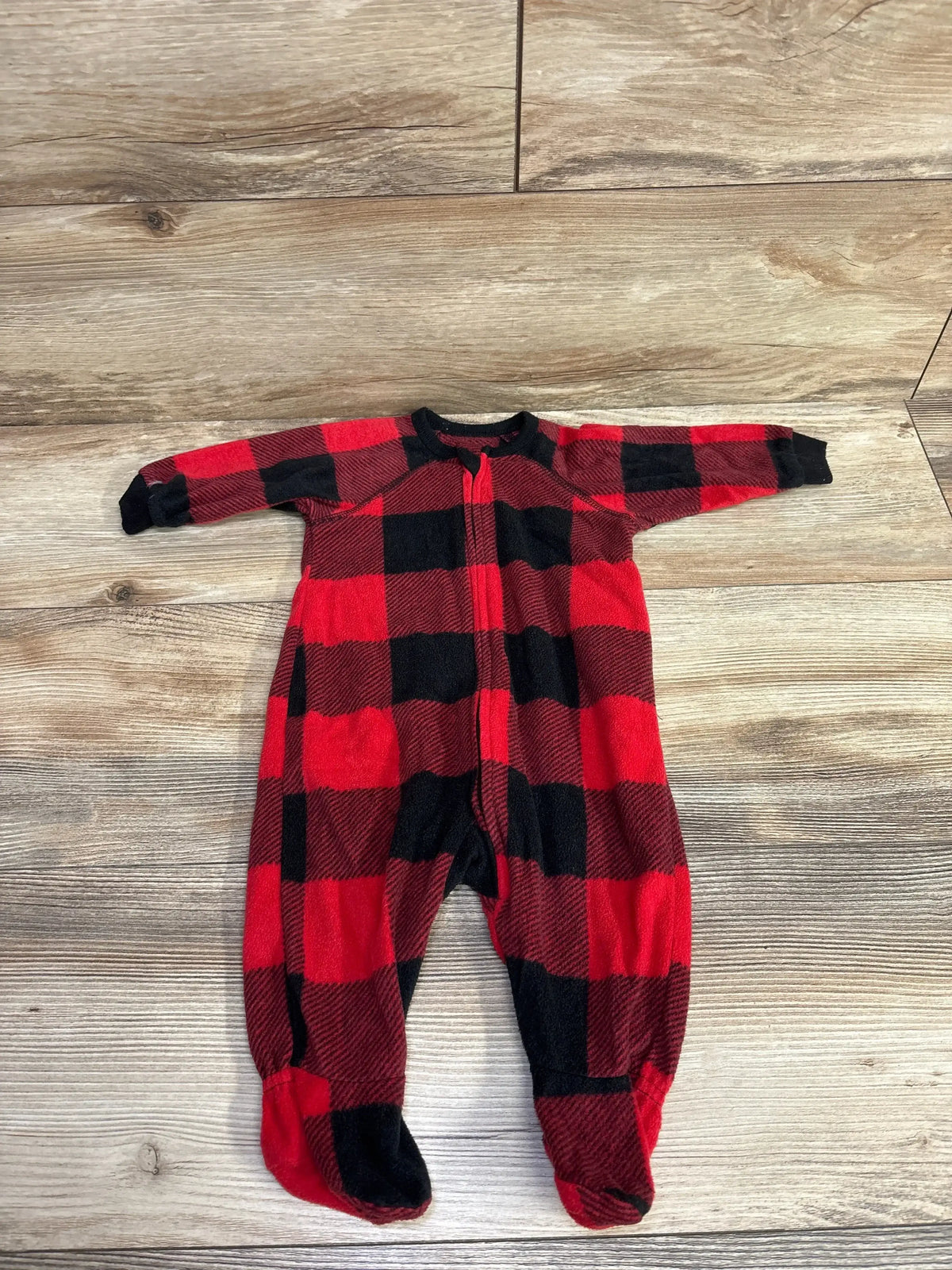 Red and black buffalo plaid fleece baby onesie with feet on wooden floor, kids clothes resale