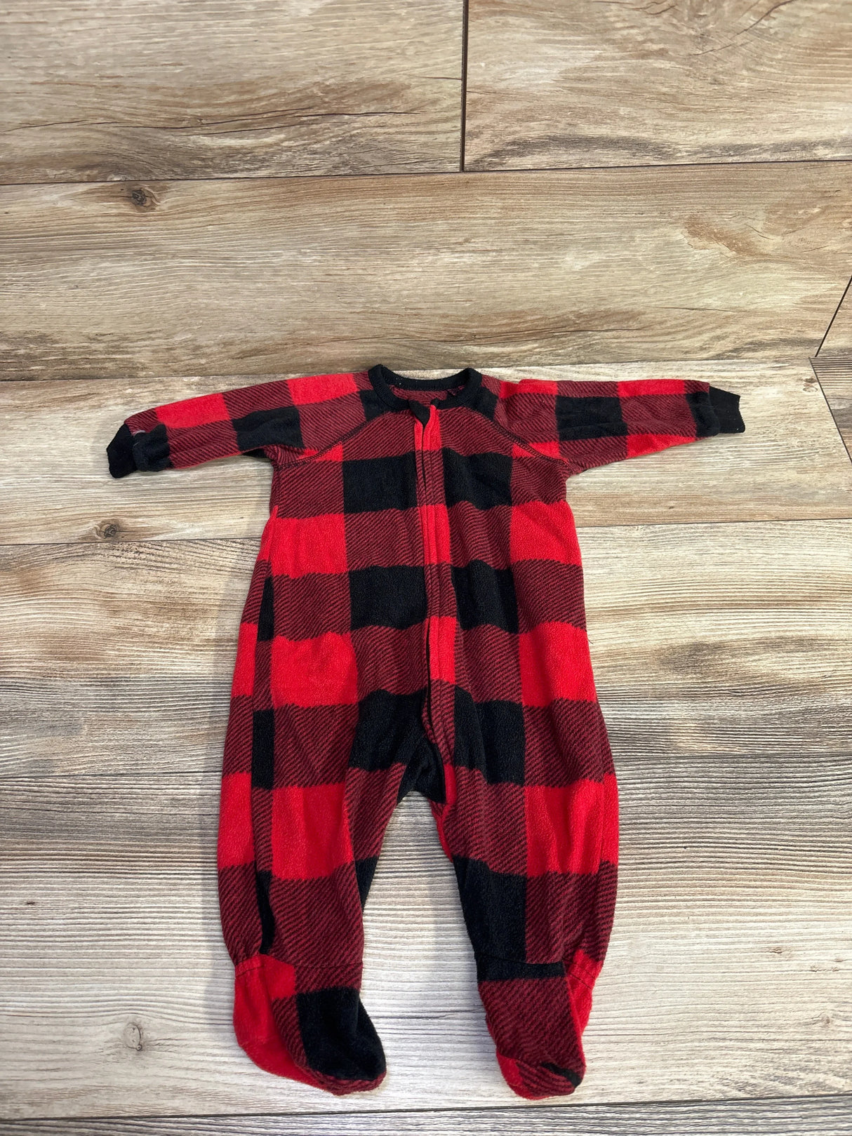 Red and black buffalo plaid fleece baby onesie with feet on wooden floor, kids clothes resale