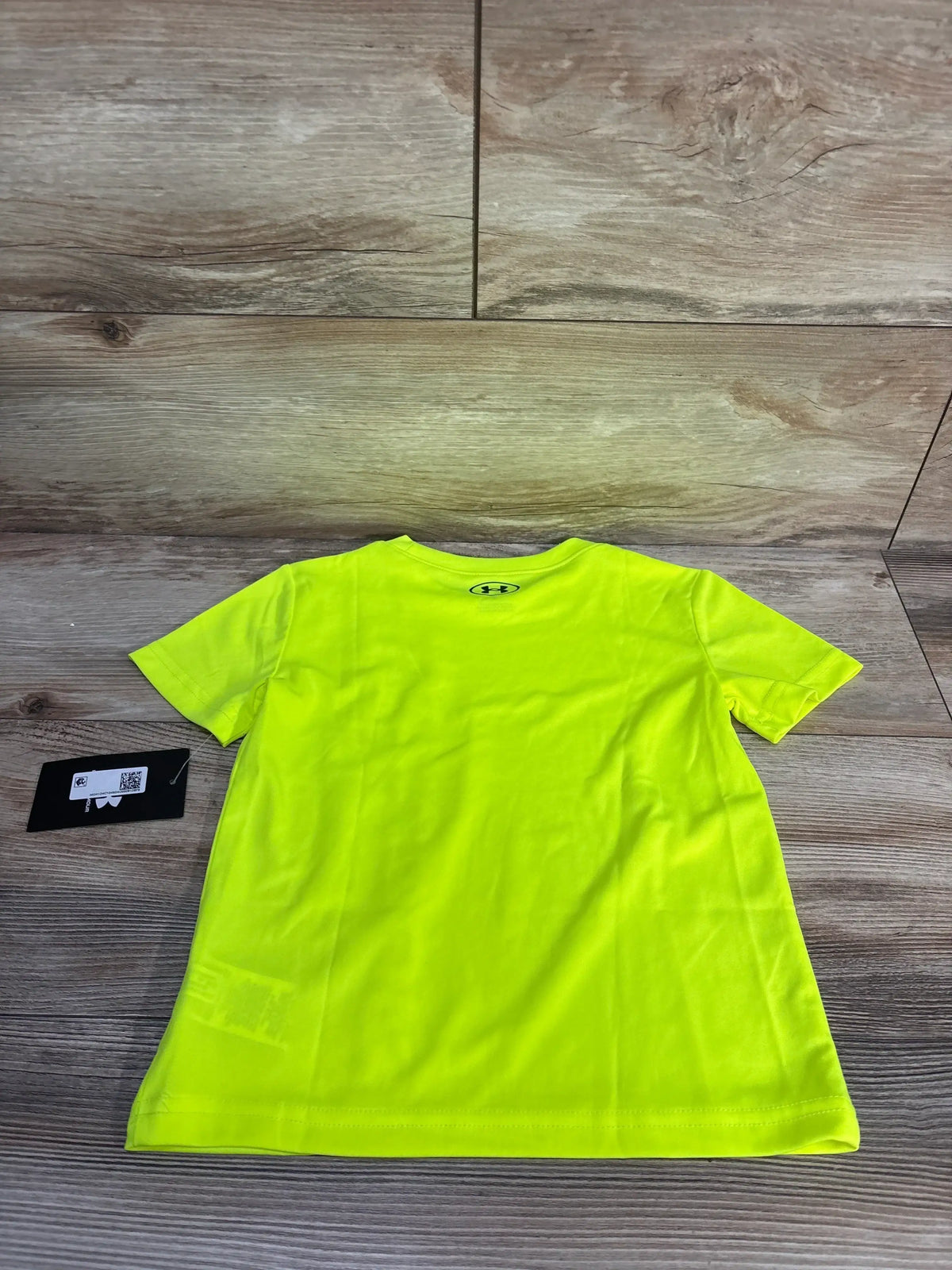 Front view of lime green Under Armour active shirt in size 4T showcasing short sleeves and crewneck on a wood floor