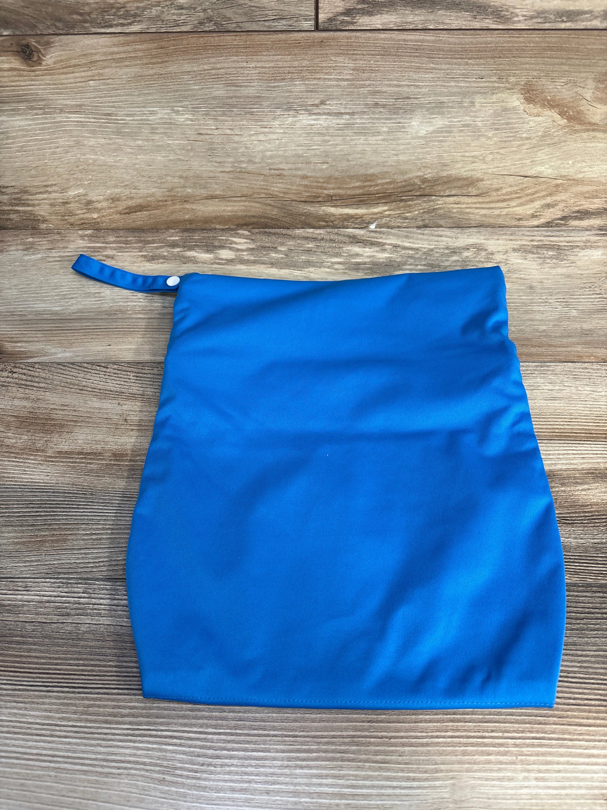 Blue reusable wet bag with snap closure on wood background
