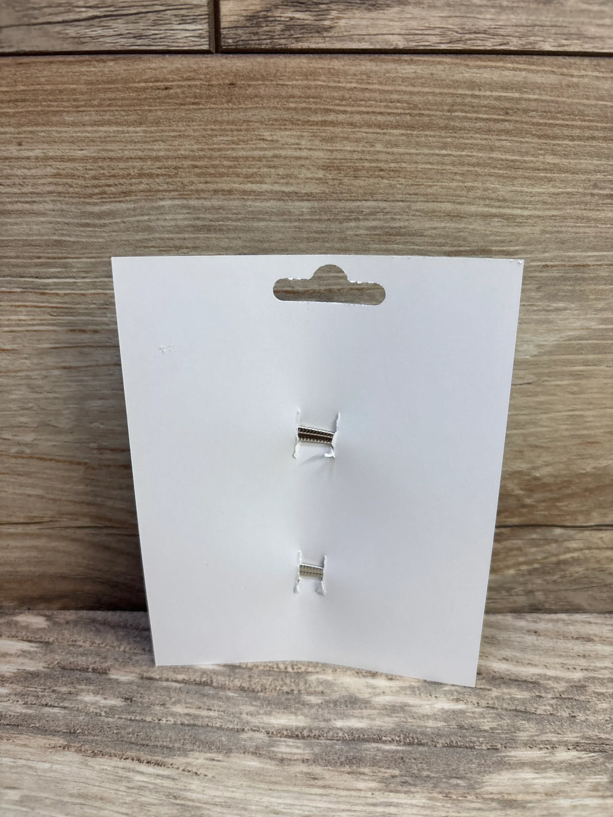 Front view of hair bows 2-pack backing card showing two small silver alligator clip bases with purple bows removed on a wood plank background