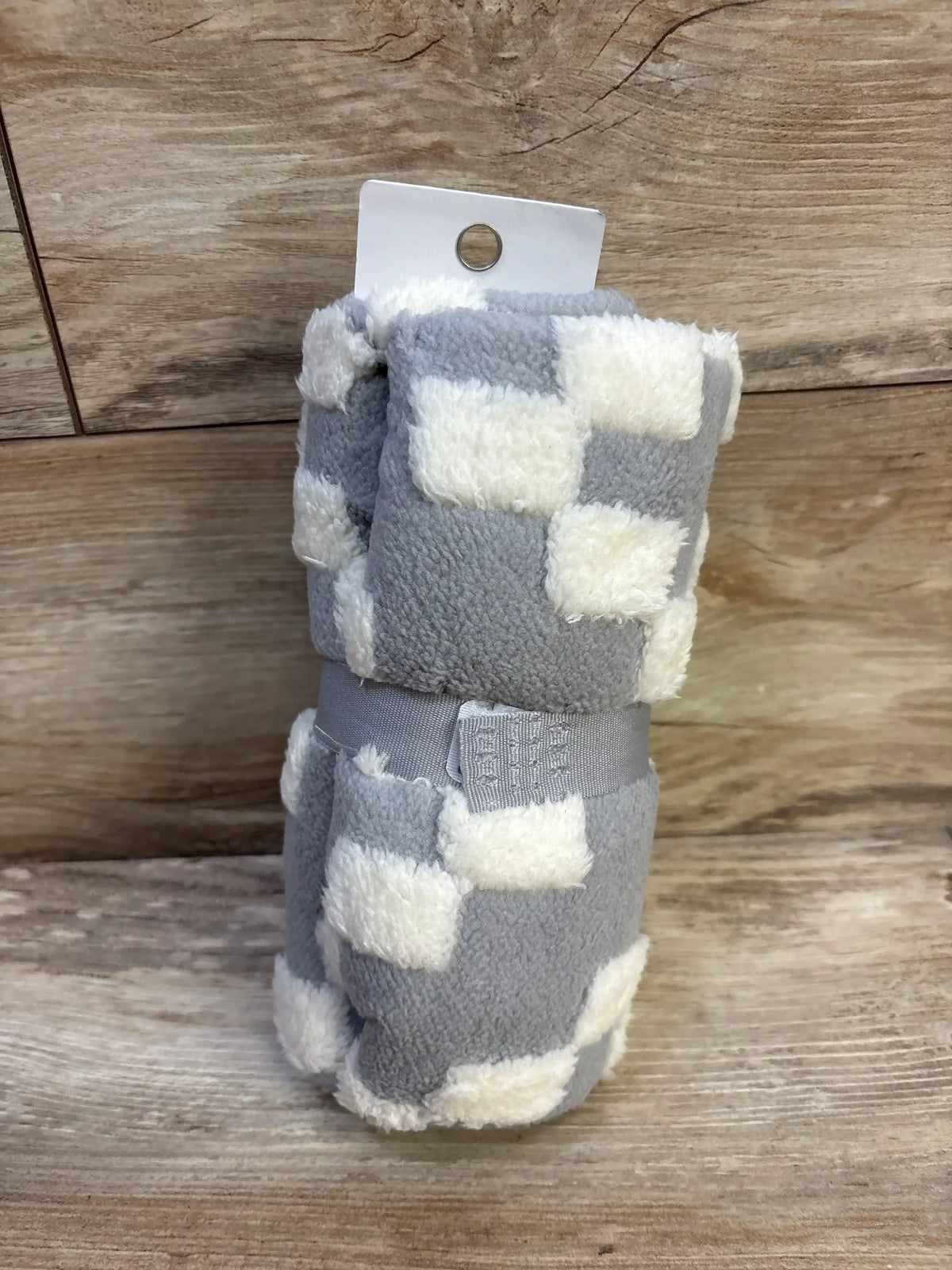 Rolled view of Cloud Island plush stroller blanket showcasing gray and white geometric squares and fluffy texture on wood background