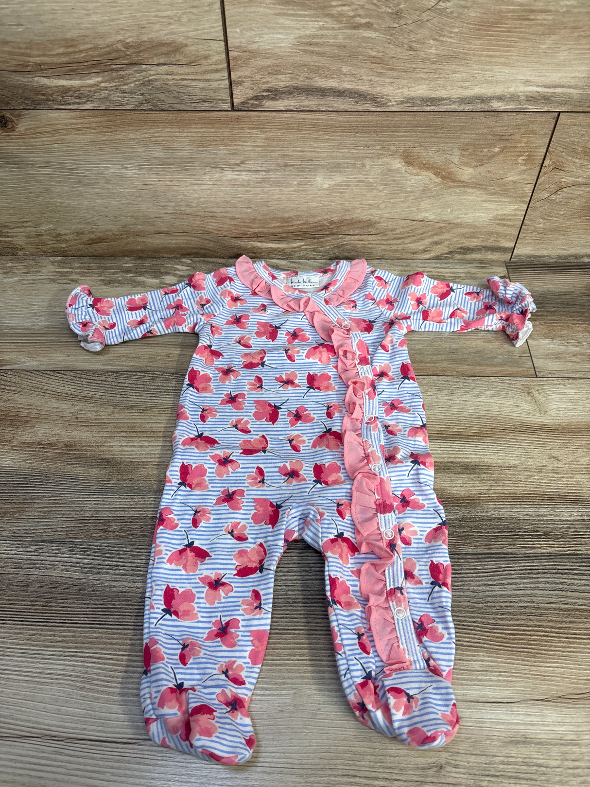 Flat lay of Nicole Miller blue striped footed coverall 3–6M with pink floral print, ruffle trim and front snaps on floor