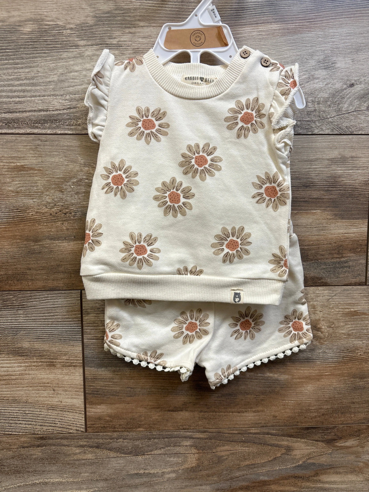 Front view of Rabbit and Bear organic ivory 2-piece sweatshirt tank and shorts set showcasing floral print, ruffled shoulders, and pom-pom trim