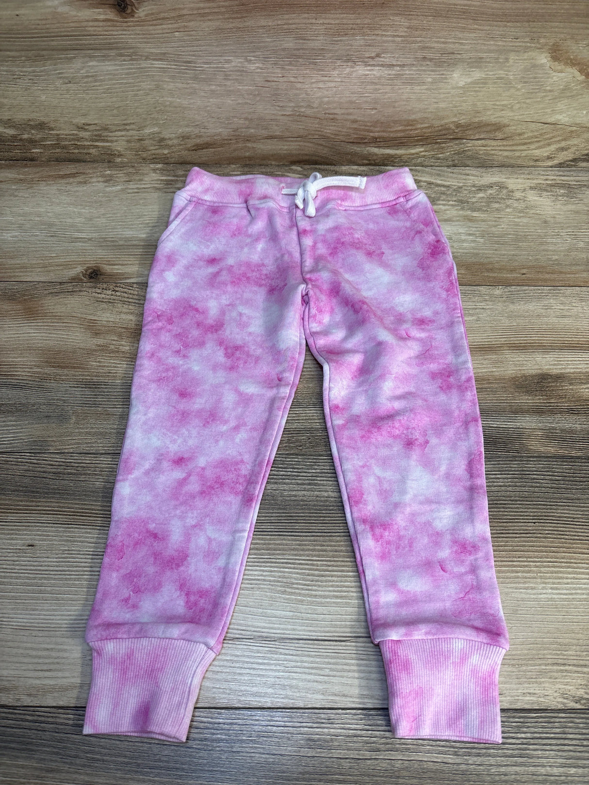 Pink and white tie-dye toddler jogger sweatpants with drawstring on wood background