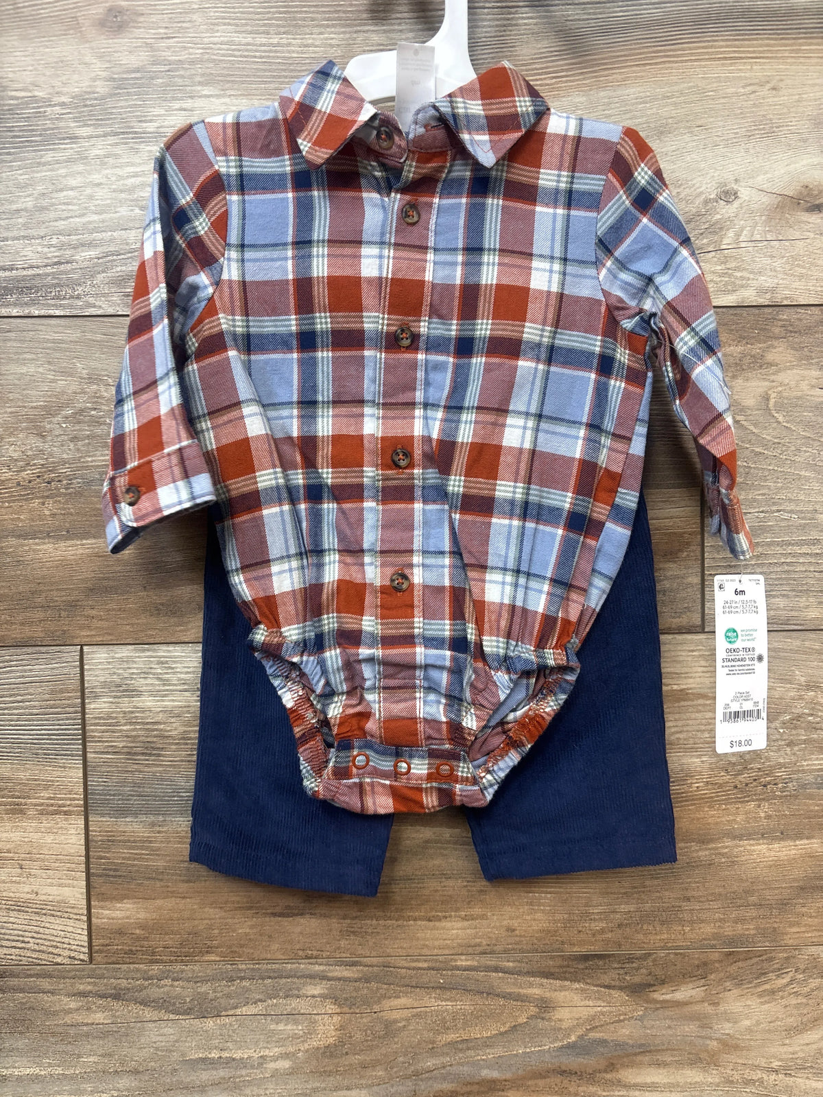 Front view of Just One You two-piece outfit with rust plaid bodysuit and navy corduroy pants on wood background