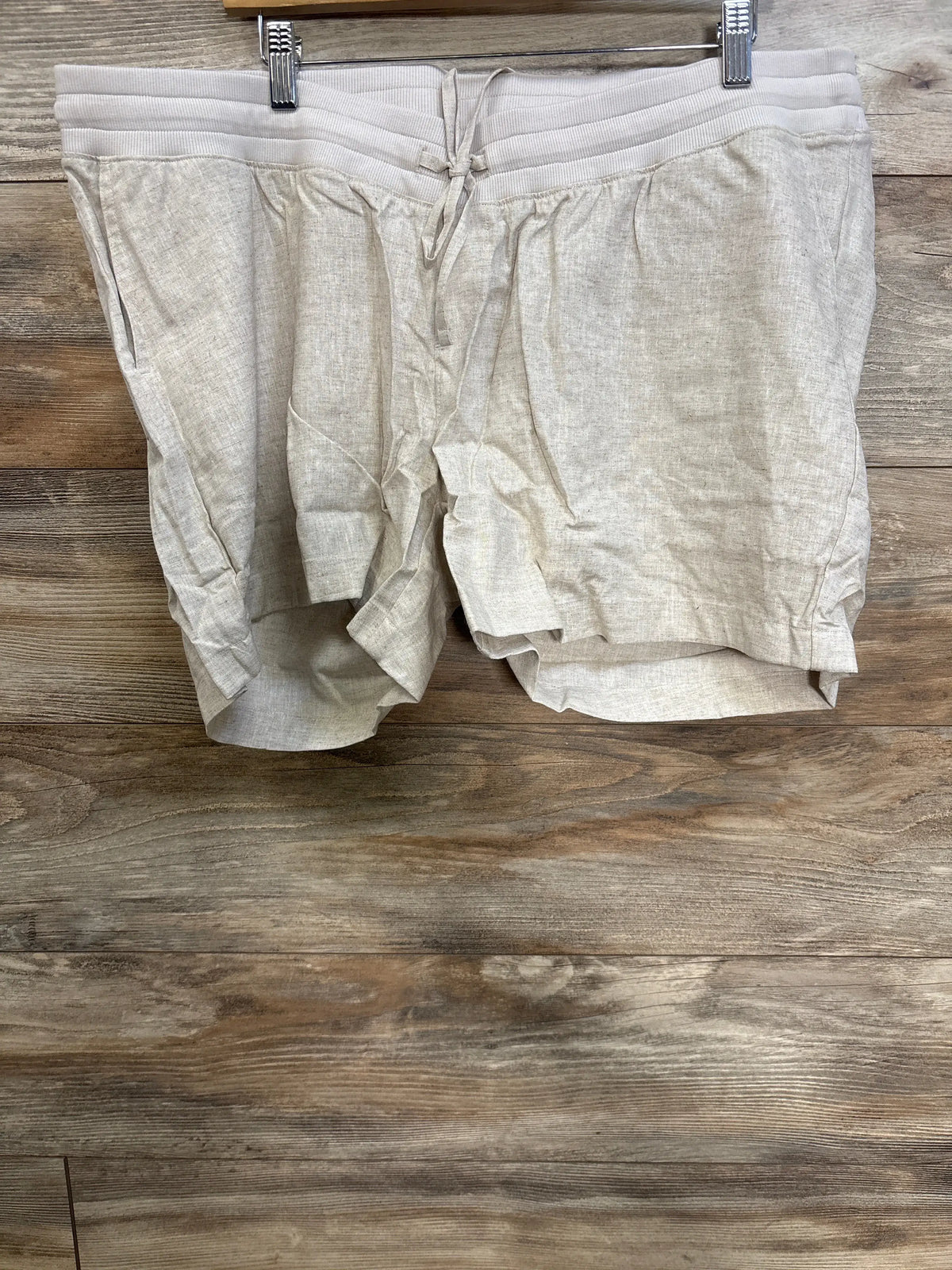 Front view of beige Gap maternity linen-blend shorts showcasing the elasticized under-belly waist and drawcords on a wood surface