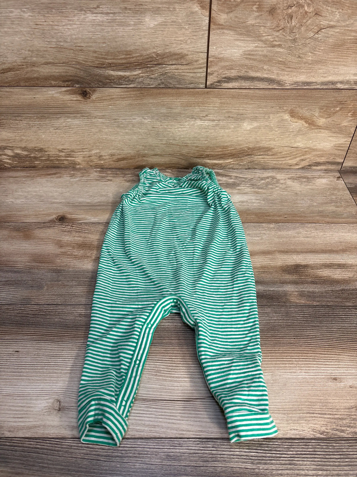 Front view of Cat & Jack striped sleeveless jumpsuit showcasing green and white stripes and snap closures with a wood-grain background