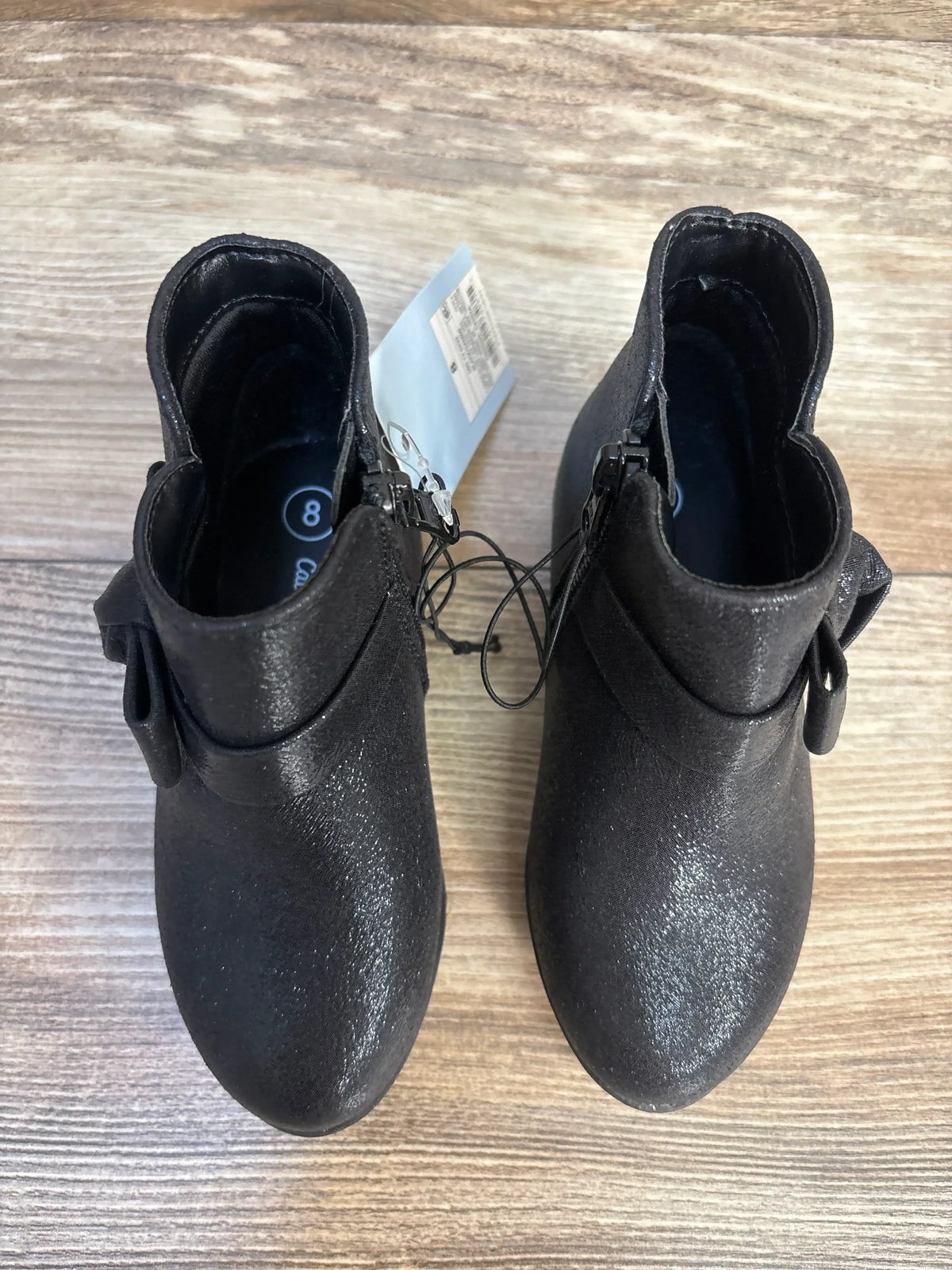 Pair of black toddler ankle boots with side zippers on wood background, size 8