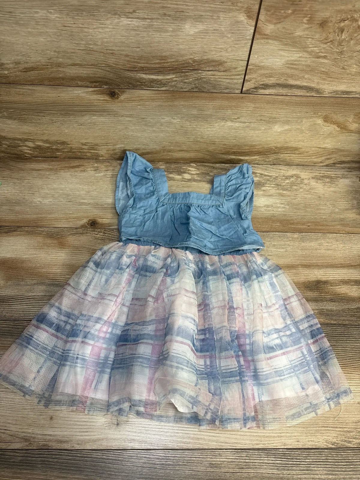 Girls' blue ruffle sleeve dress with pastel plaid tulle skirt on wood background.