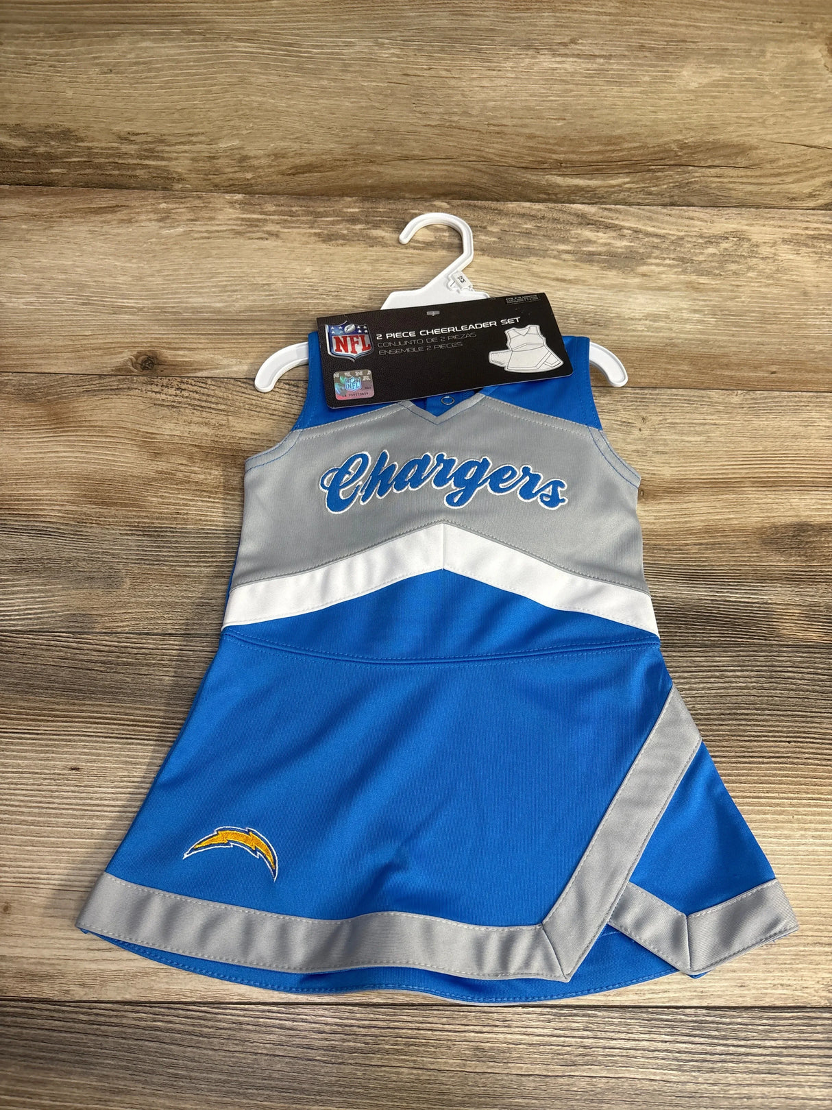 Toddler NFL Chargers cheerleader dress in blue, gray, and white with team logo on wooden background