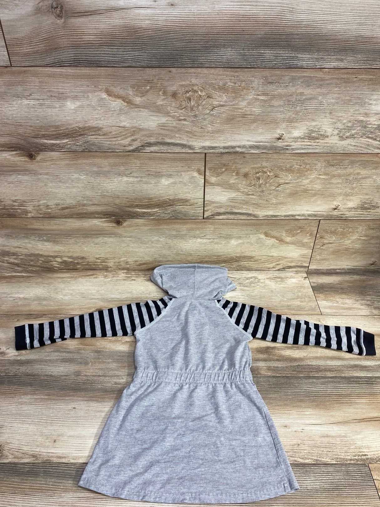 Gray hooded kids dress with black and gray striped long sleeves on wooden floor