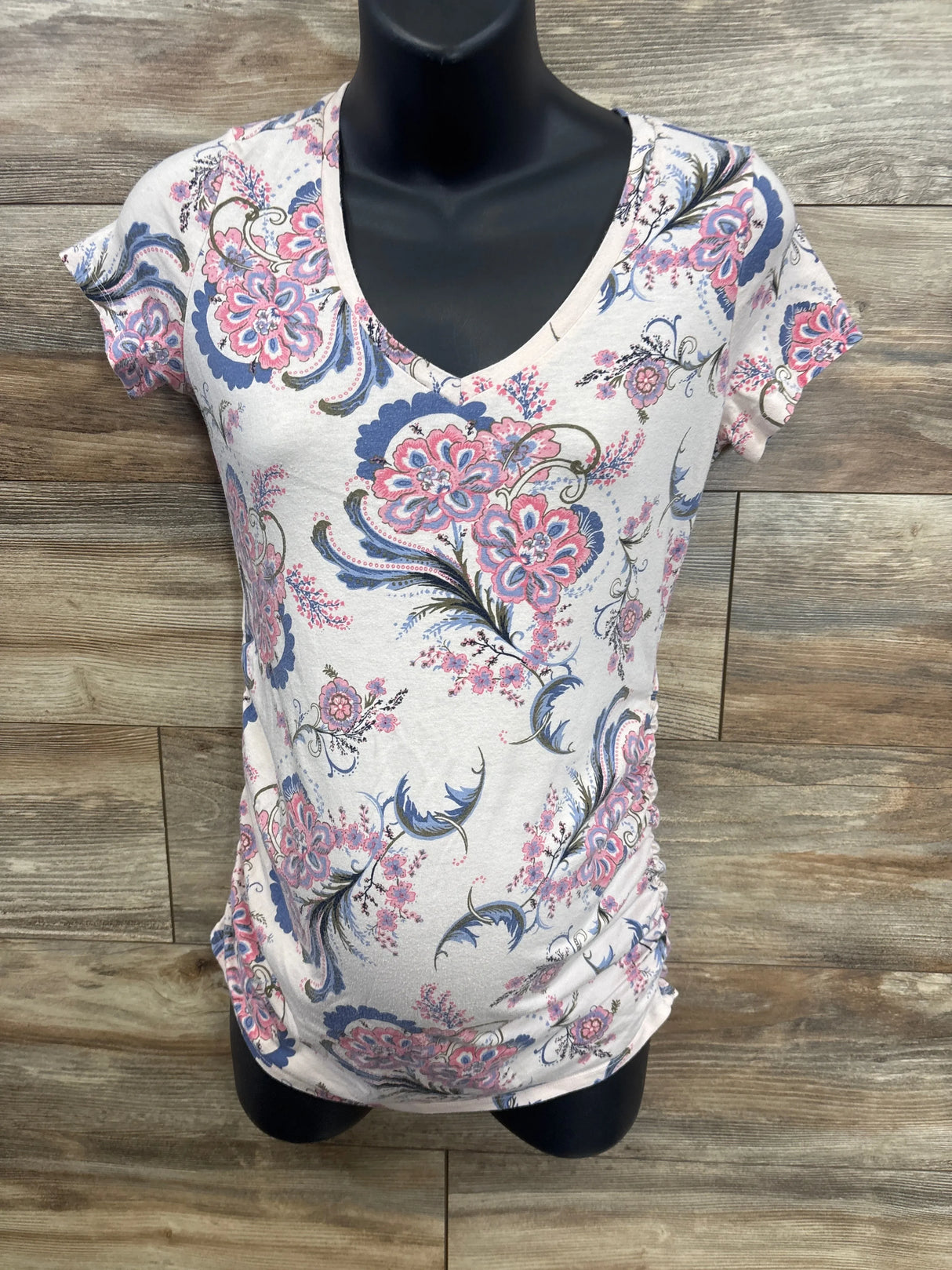 Floral maternity t-shirt with short sleeves and v-neck on a mannequin, wood background