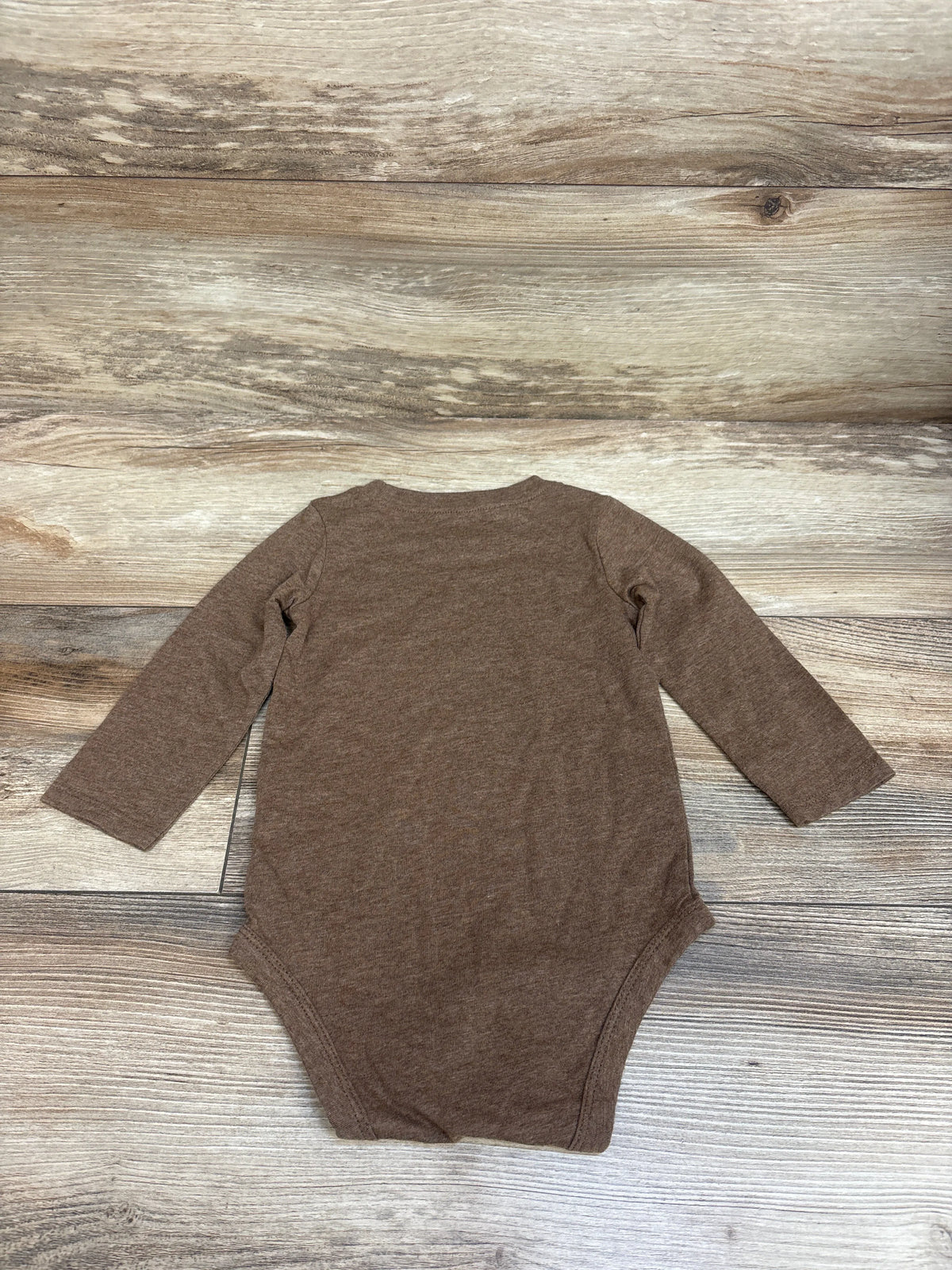 Front view of Carter’s brown football bodysuit with long sleeves on a wood-grain background