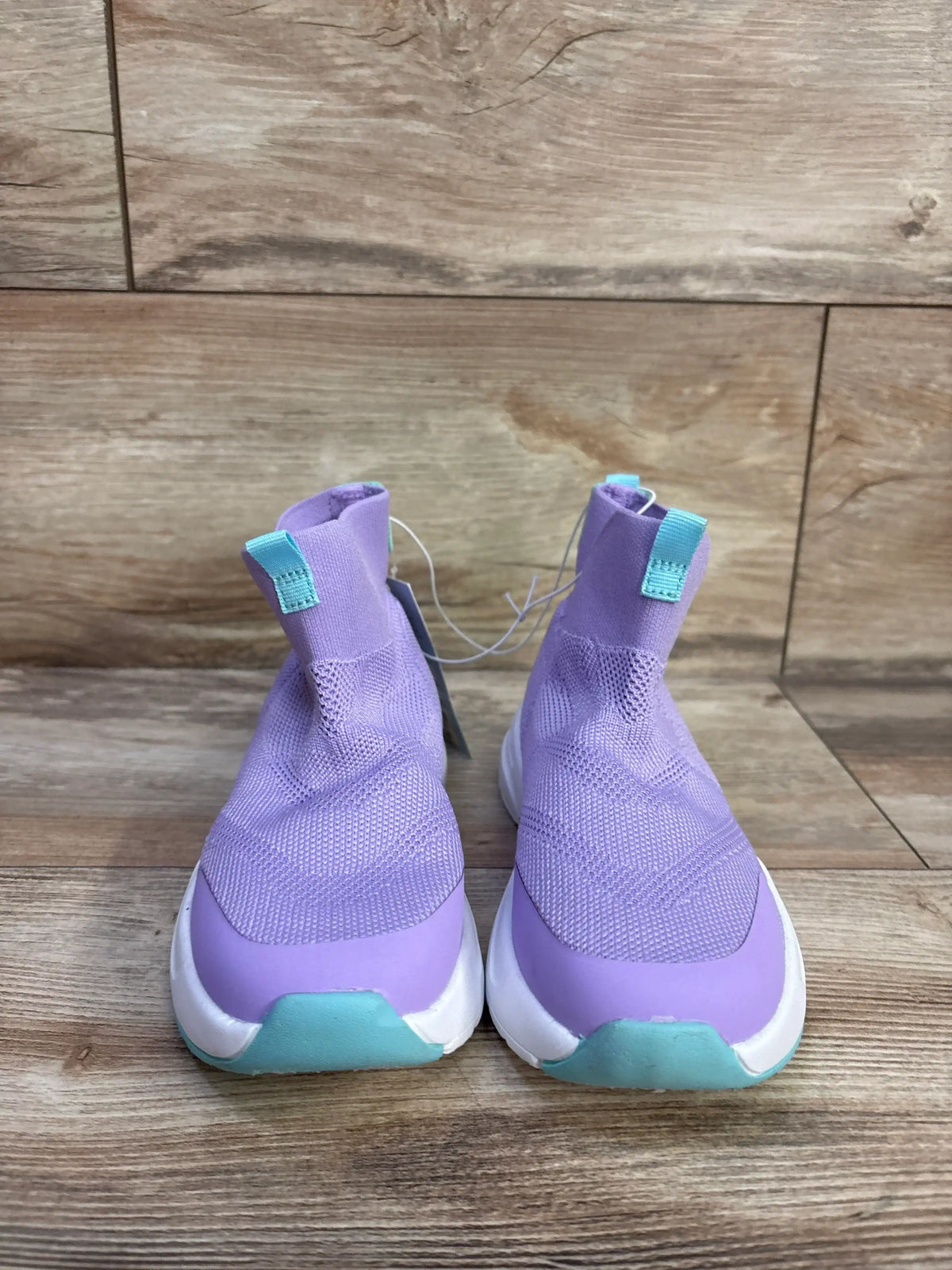 Front view of purple Cat and Jack Ari toddler sock sneakers showing knit upper, teal pull tabs and white sole on wood floor