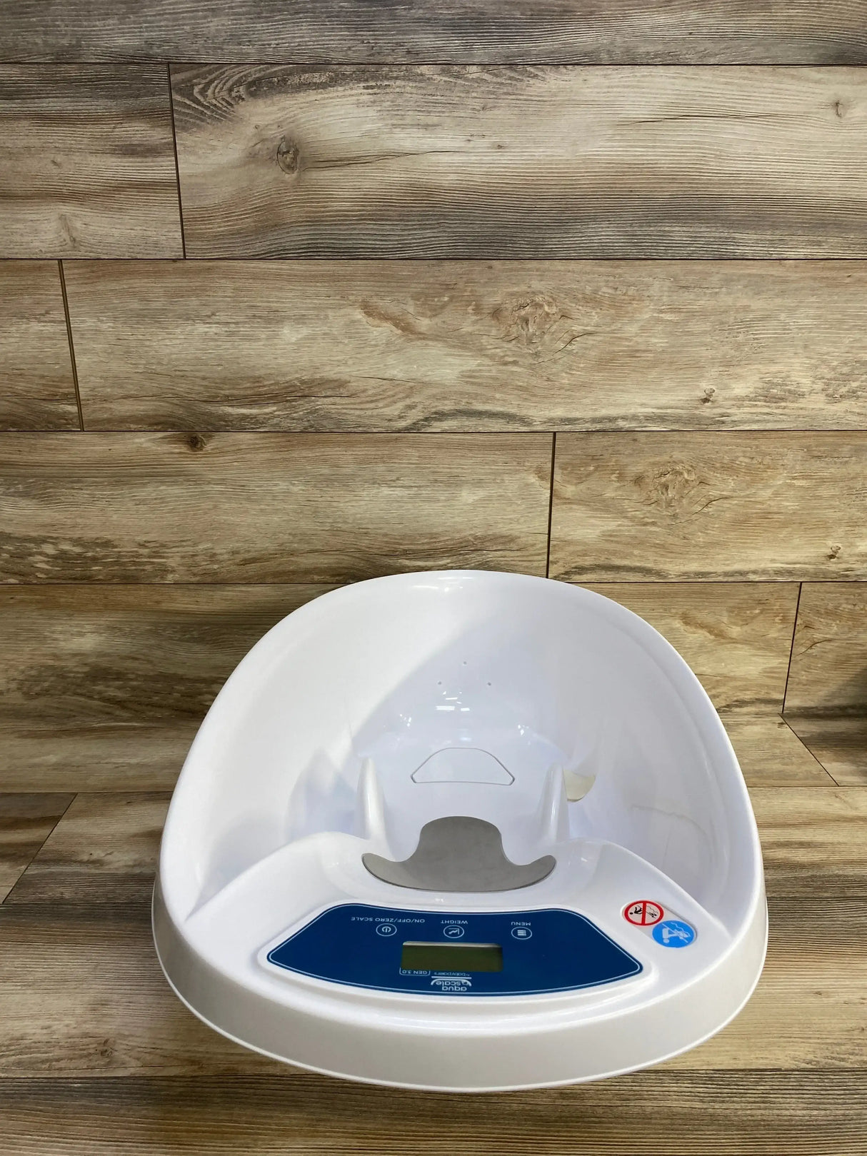 Top-front view of AquaScale 3-in-1 tub showcasing contoured gray seat and front blue digital scale panel on wood background