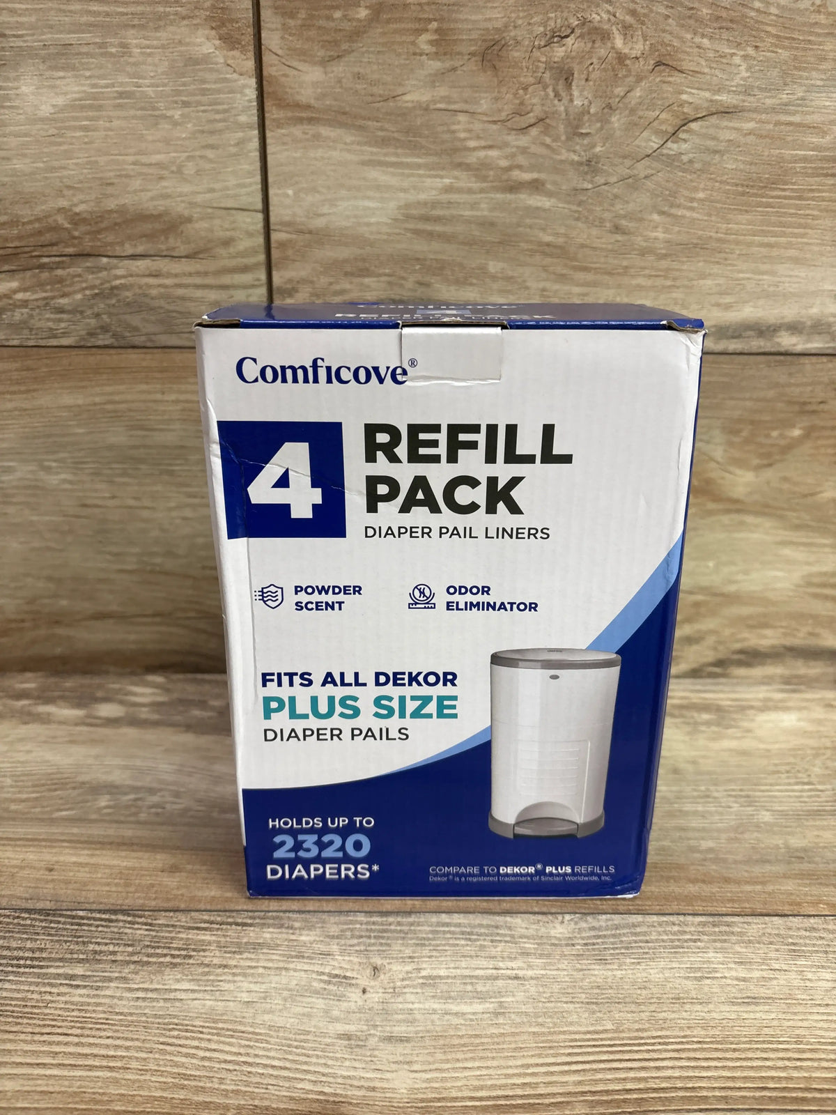 Front view of Comficove DEKOR PLUS diaper pail liner refill 4-pack showing up to 2320 diapers on wood-patterned background